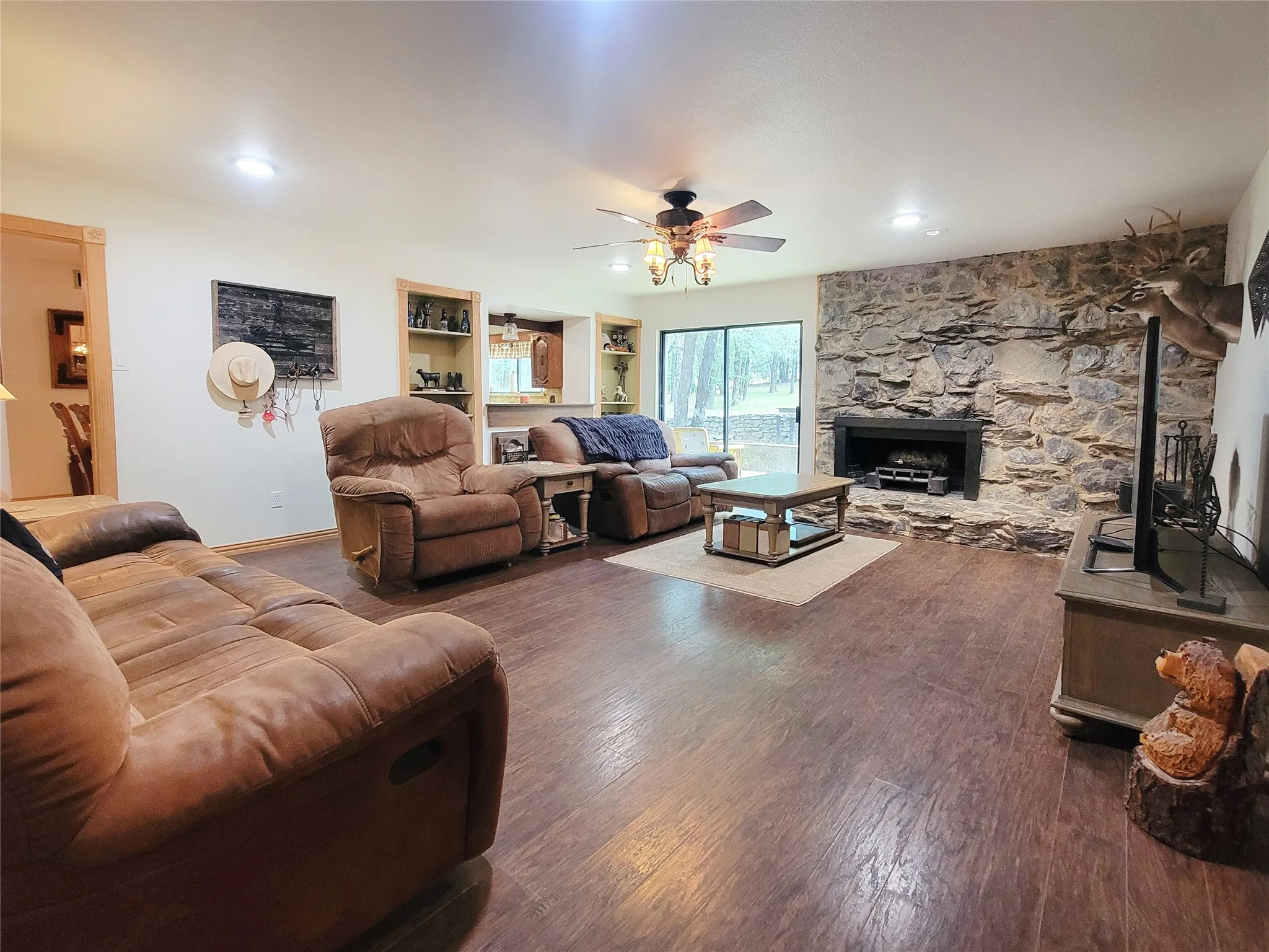 Wood-finish flooring throughout, complemented by a stone-clad fireplace with a dark-finish mantel