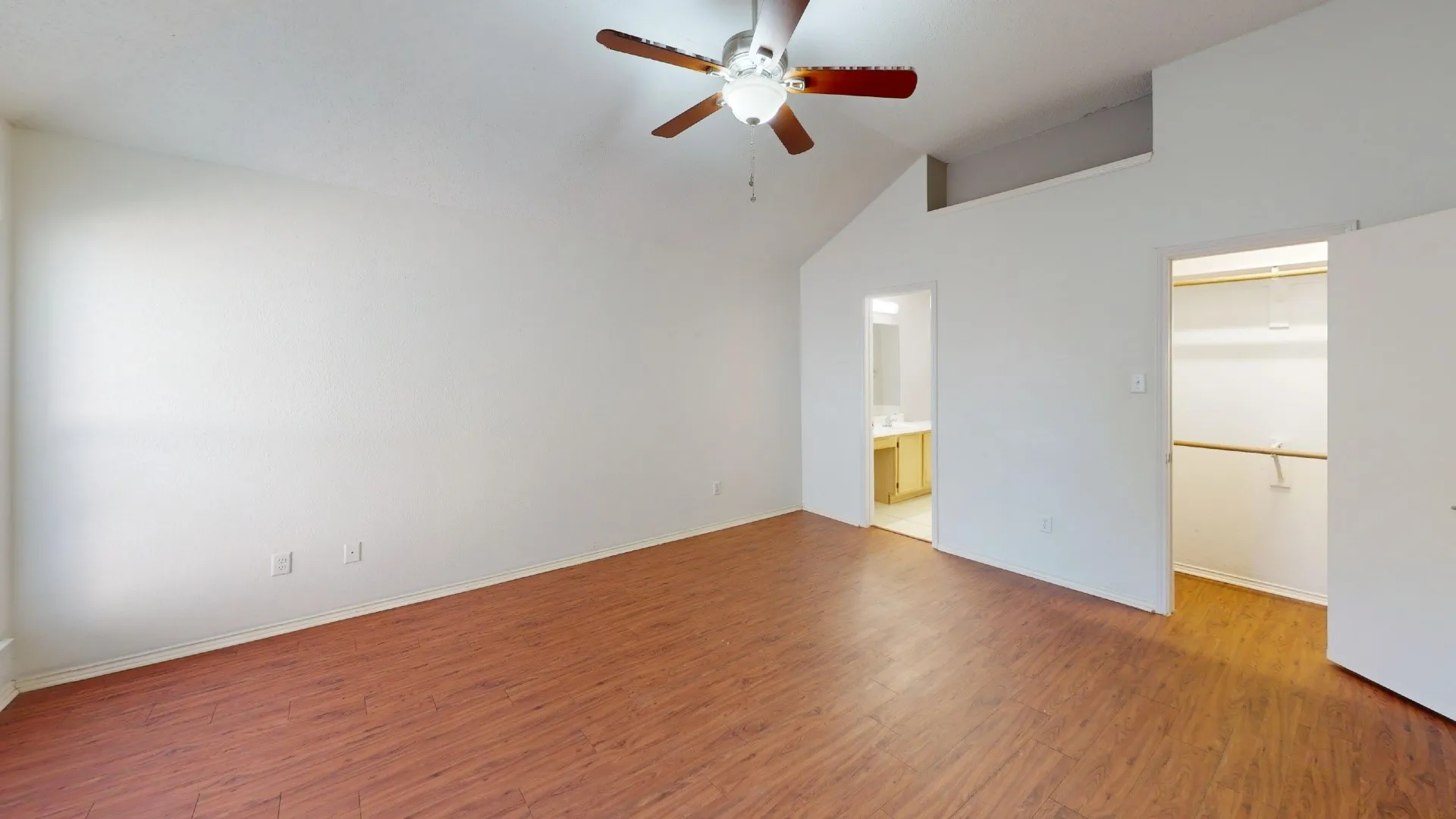 Room featuring vaulted ceilings, wood-finish flooring, a ceiling fan with integrated lighting, and a built-in closet