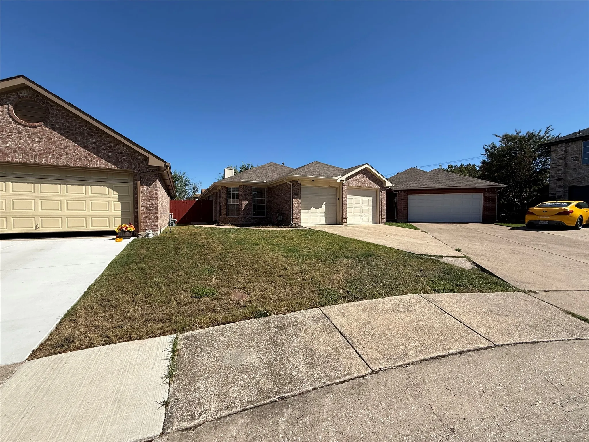 Brick exterior residence featuring a two-car garage, concrete driveway, and front lawn
