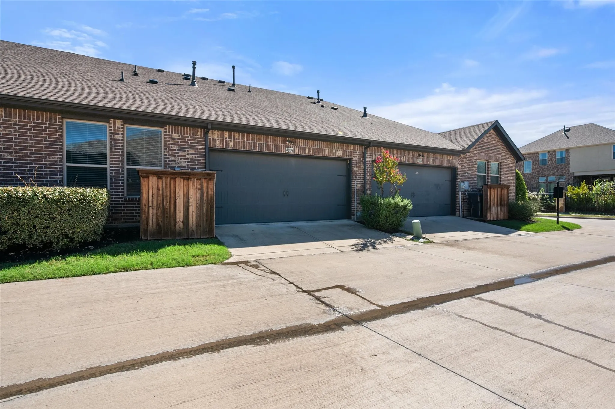 Brick exterior with a dark shingle roof, attached garages with dark doors, and concrete driveways