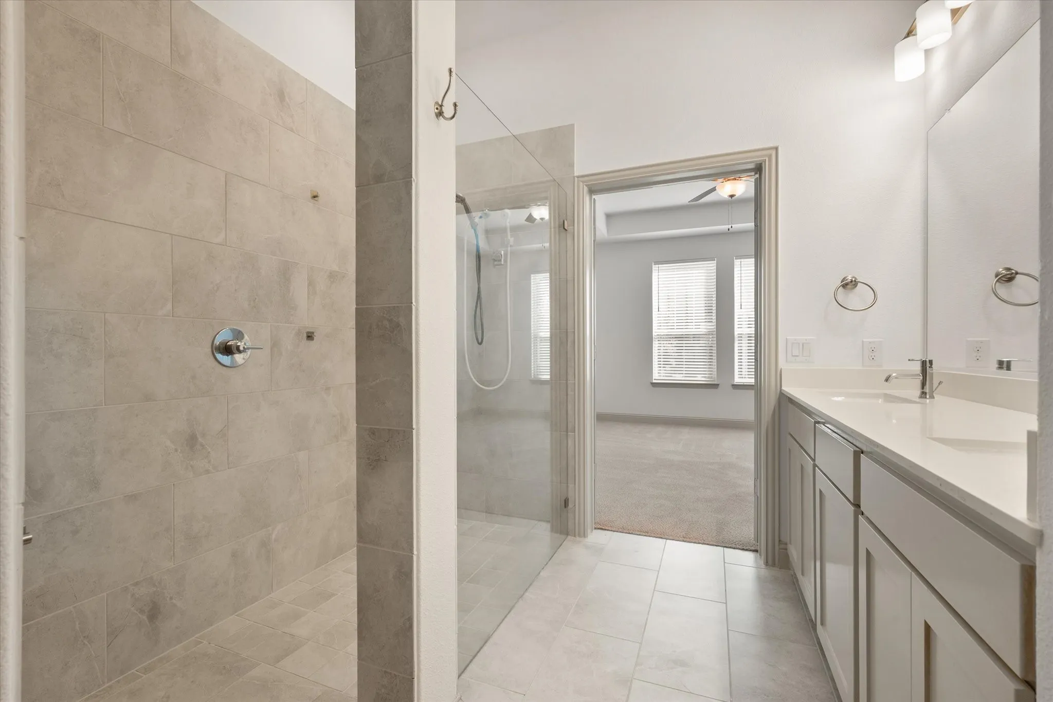 Dual-sink vanity with light-colored countertops, large wall-mounted mirror, and tile flooring