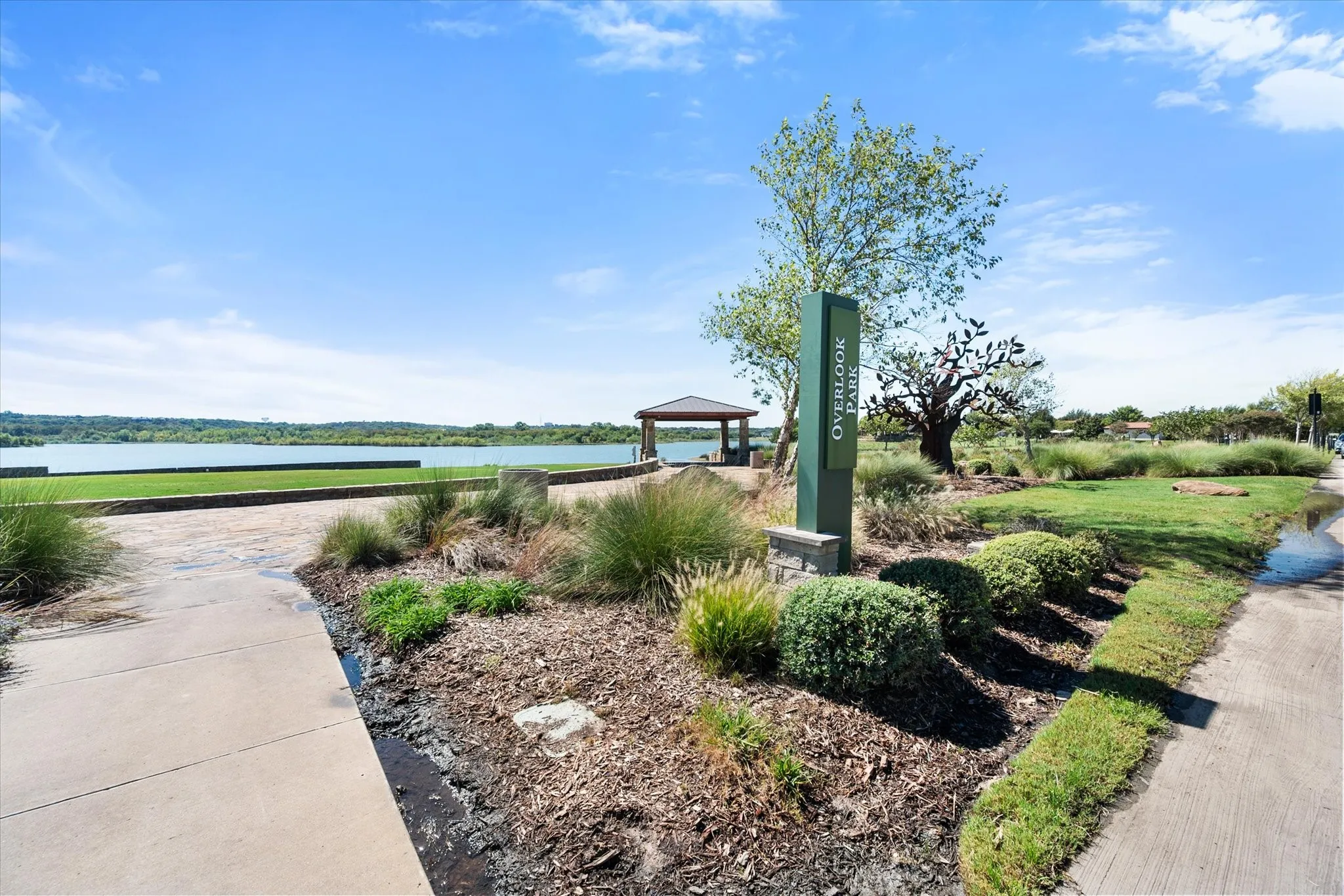 Expansive waterfront with a paved walkway, a gazebo, and a manicured lawn