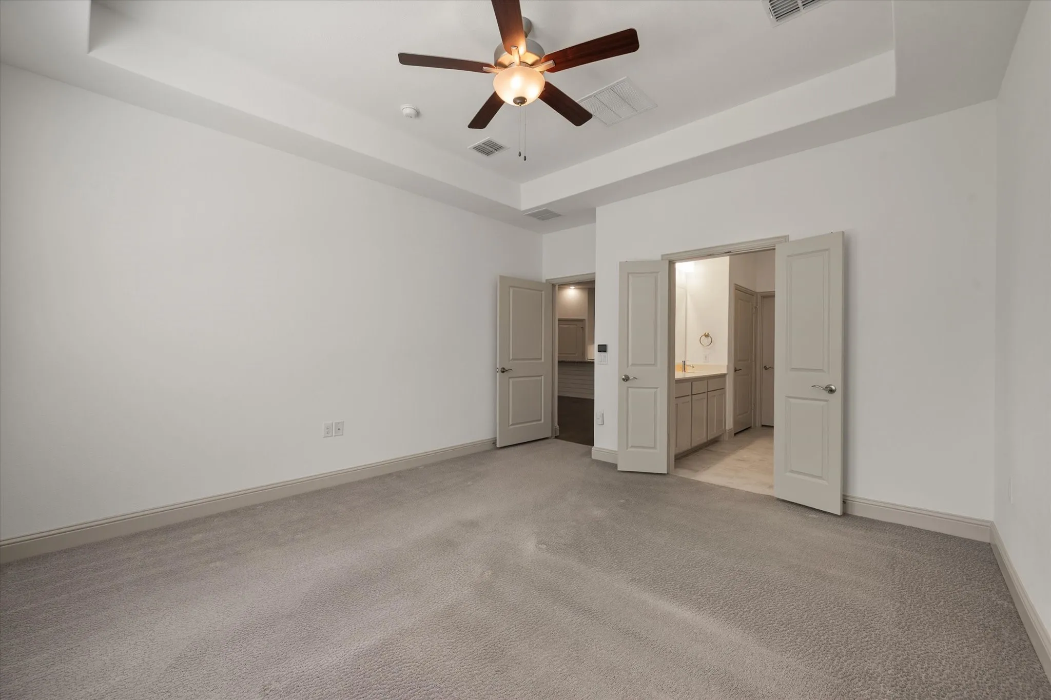 Recessed ceiling with a flush-mount ceiling fan, neutral carpeting, and light-toned baseboards