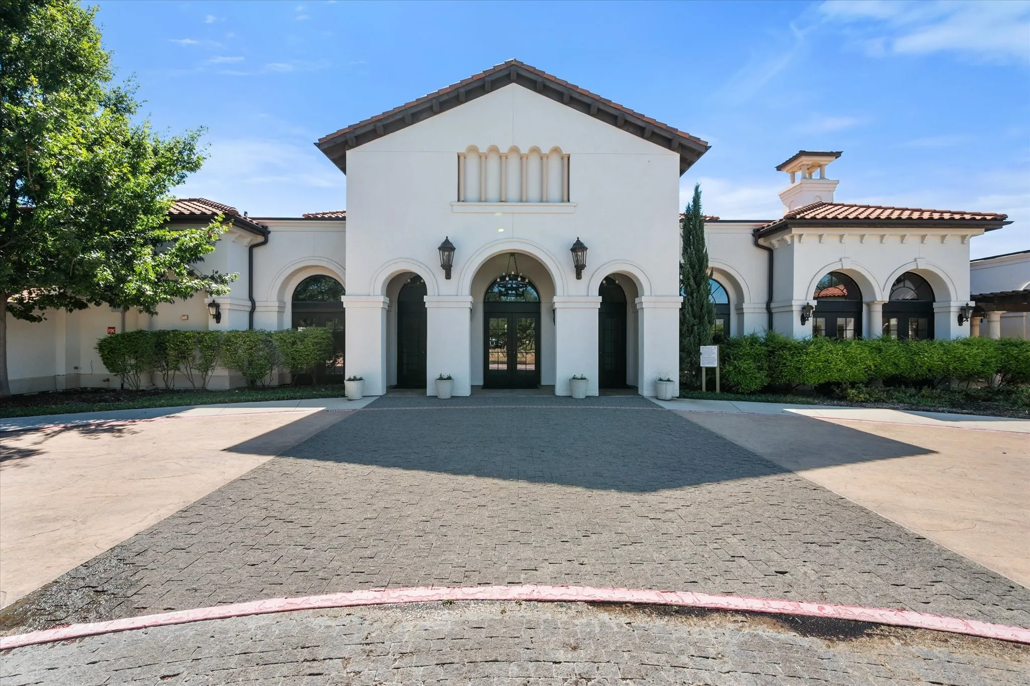 Stucco exterior with arched entryways, a paver driveway, and a tile roof