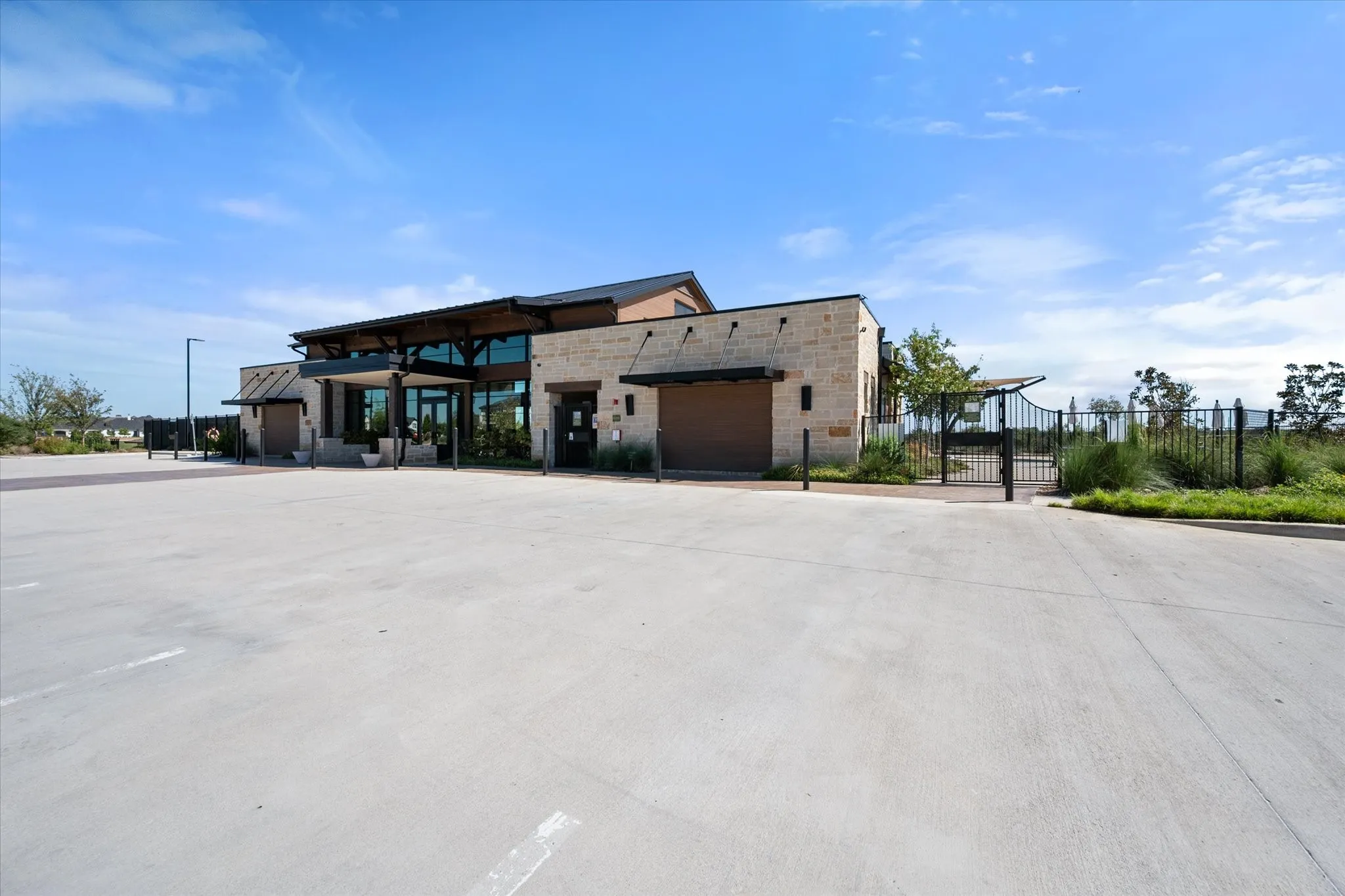 Stone exterior with a dark-stained wood-beam overhang and a large concrete parking lot