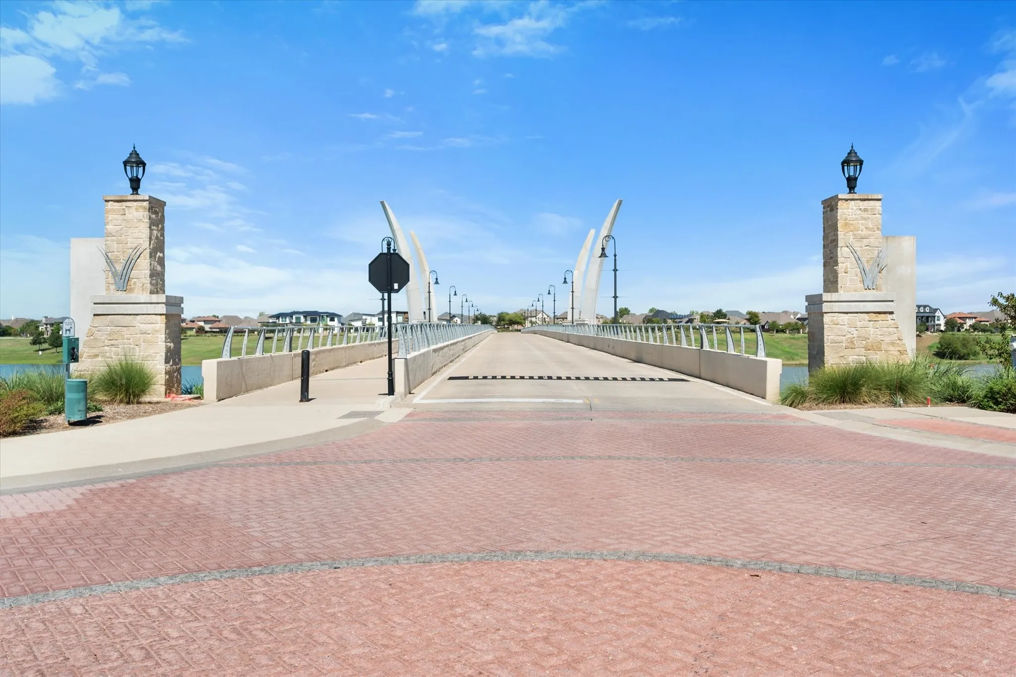 Brick paver entry with stone pillars, featuring integrated lighting and architectural bridge elements