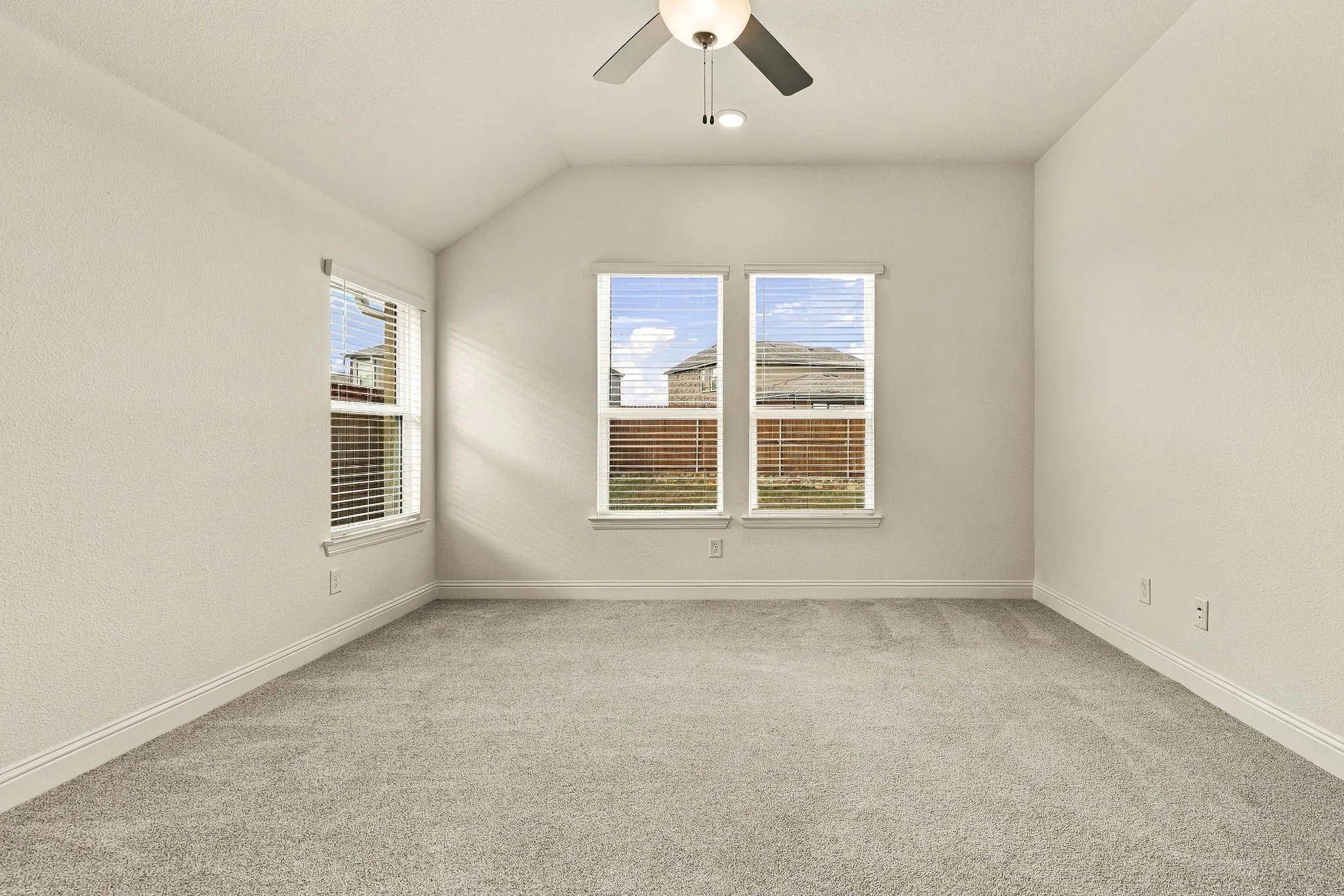 Room featuring neutral wall tones, plush wall-to-wall carpeting, three multi-pane windows, and a ceiling-mounted light fixture with a fan