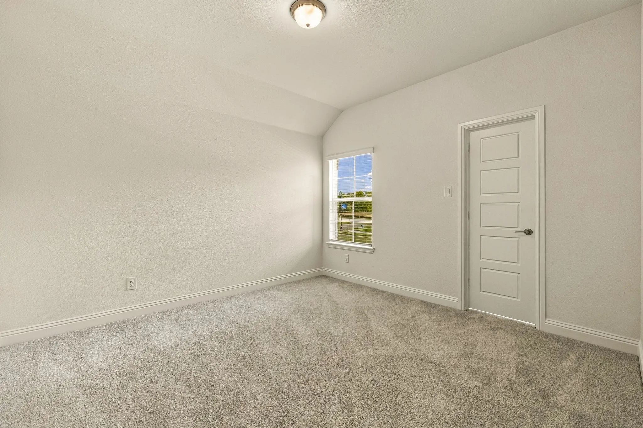 Neutral interior space featuring high ceilings, wall-to-wall carpeting, a single-hung window, and a five-panel interior door