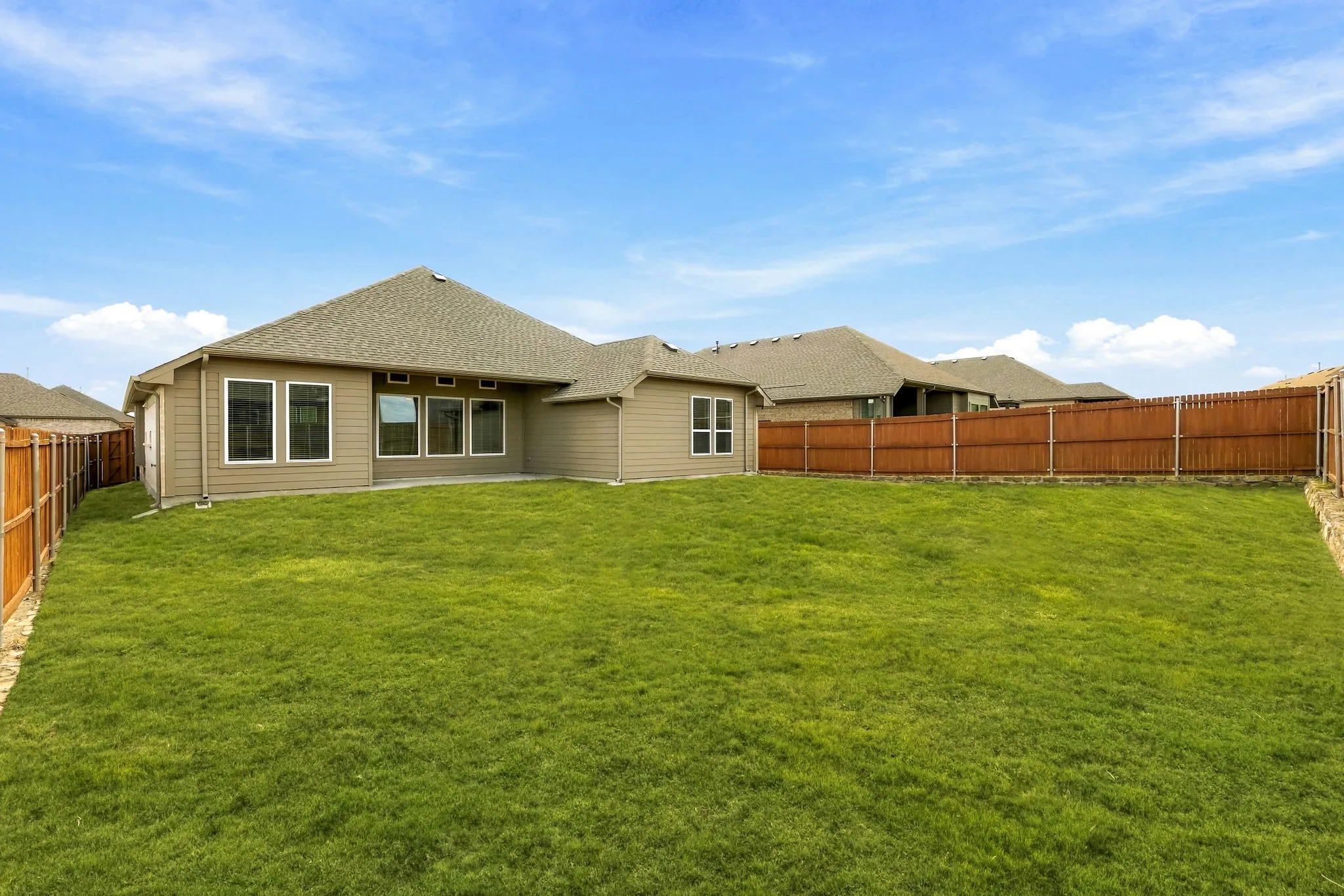 Backyard featuring a manicured lawn, horizontal wood-slat privacy fencing, and rear exterior elevation with light-toned siding