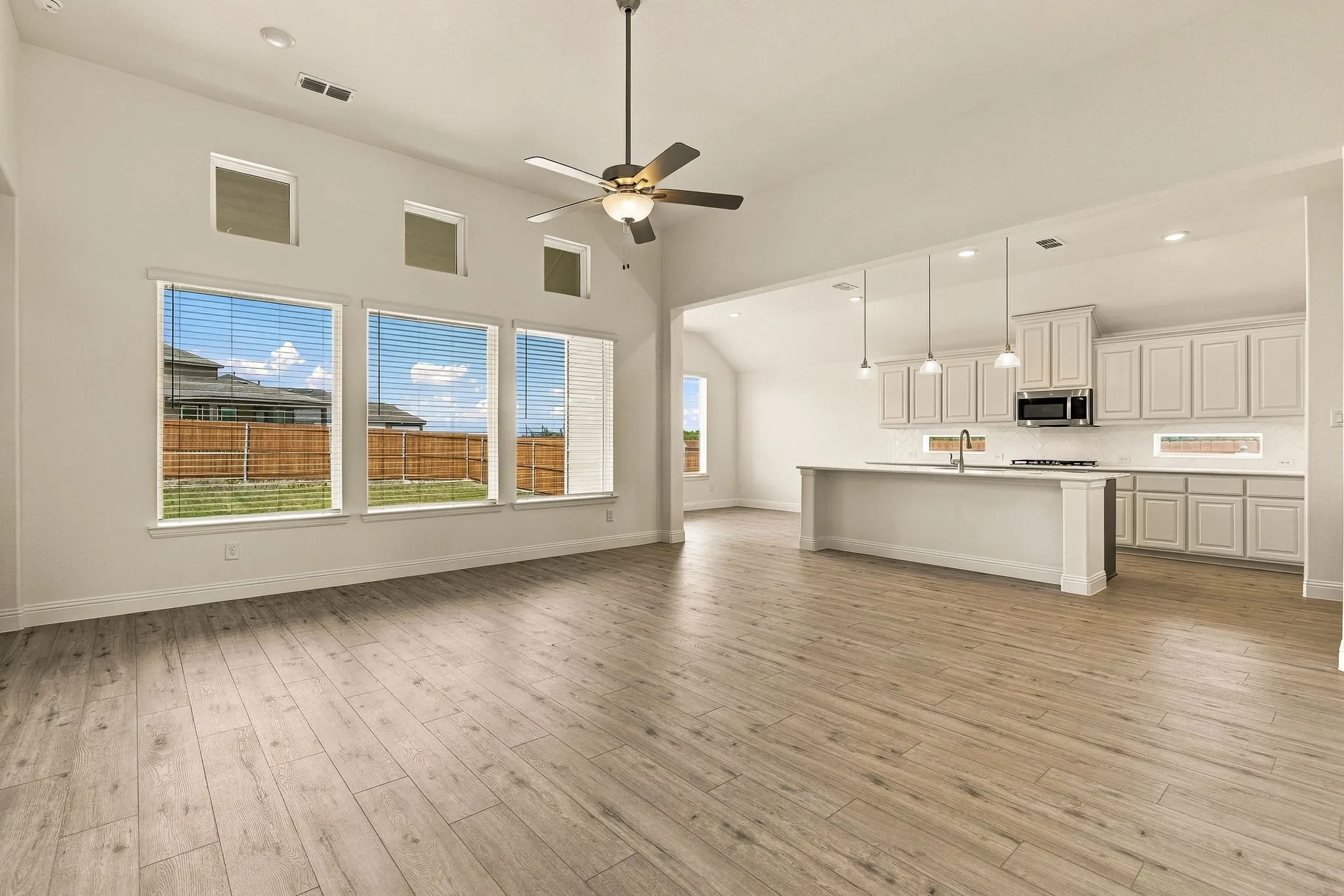 Vaulted ceilings, wood-finish flooring, oversized windows with transoms, kitchen island with built-in cabinetry, and pendant lighting