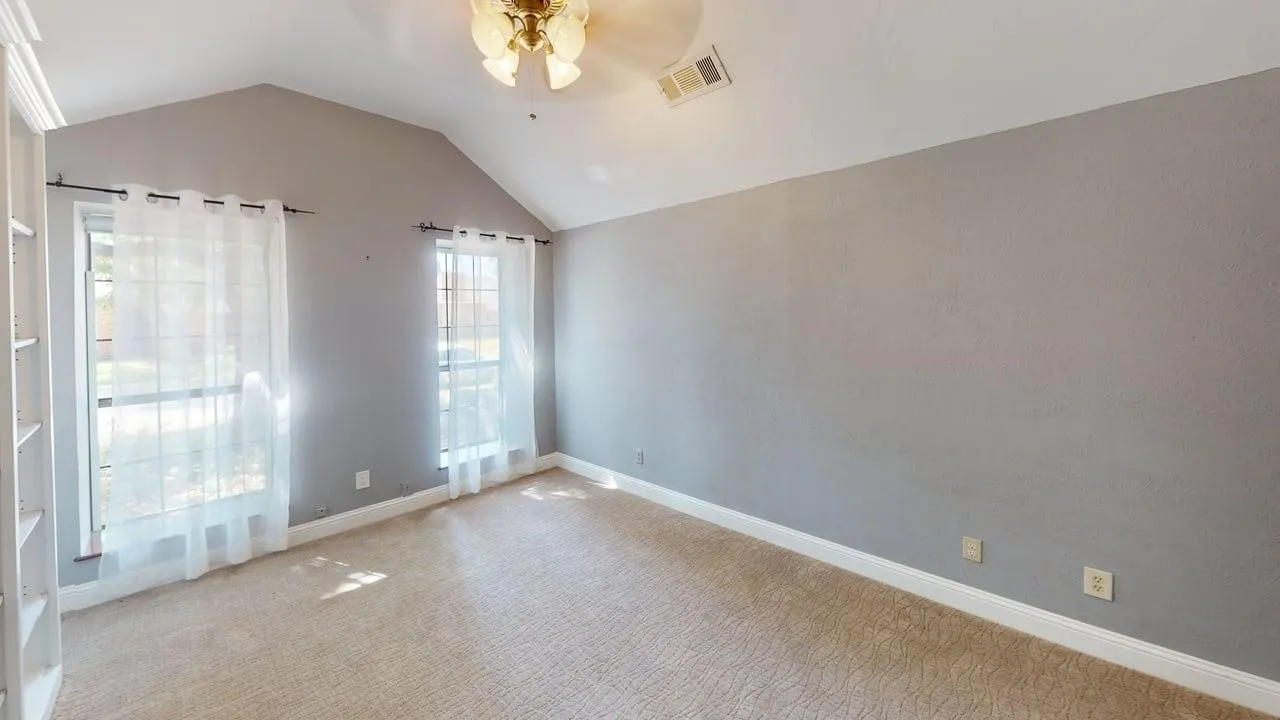 Vaulted ceiling, neutral wall tones, two tall windows with grid detailing, and built-in white shelving