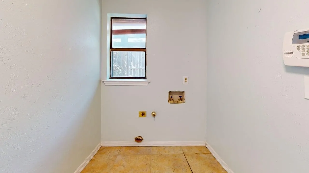 Laundry area featuring tile flooring, a single-hung window, and wall-mounted security system control panel