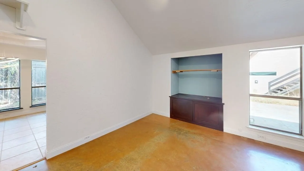 Vaulted ceilings, stained concrete flooring, and a built-in cabinet with recessed shelving