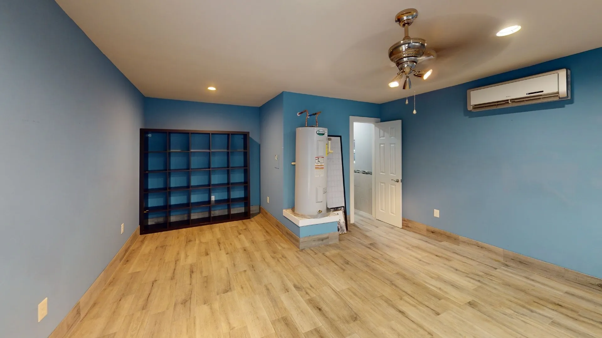 Interior space featuring wood-finish flooring, a wall-mounted ductless mini-split system, recessed lighting, and a ceiling fan with integrated light fixture