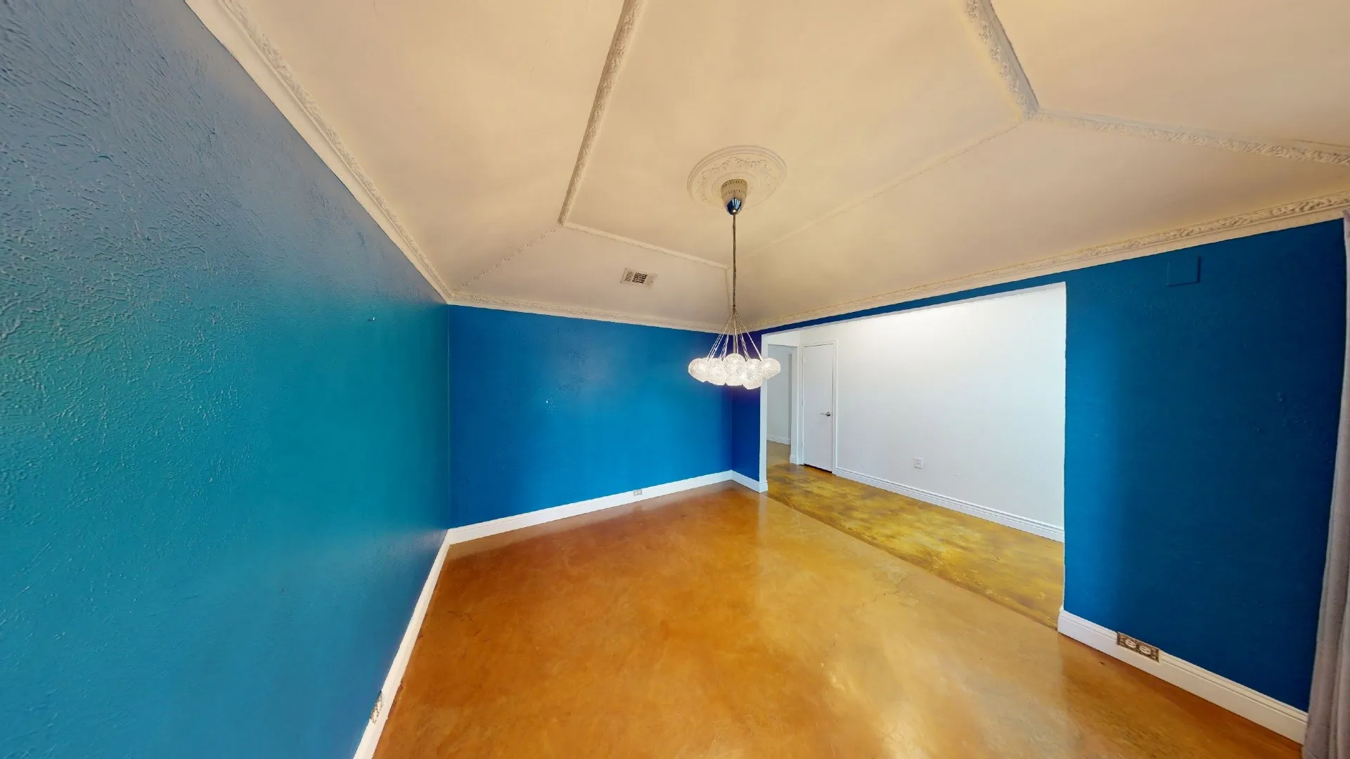 Tray ceiling featuring detailed crown molding, accompanied by a multi-bulb pendant light fixture and wood-finish flooring