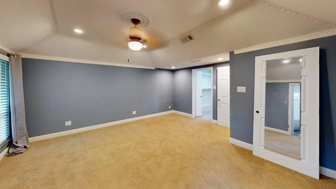 Tray ceiling with crown molding, ceiling fan with decorative medallion, recessed lighting, and wall-mounted mirror door