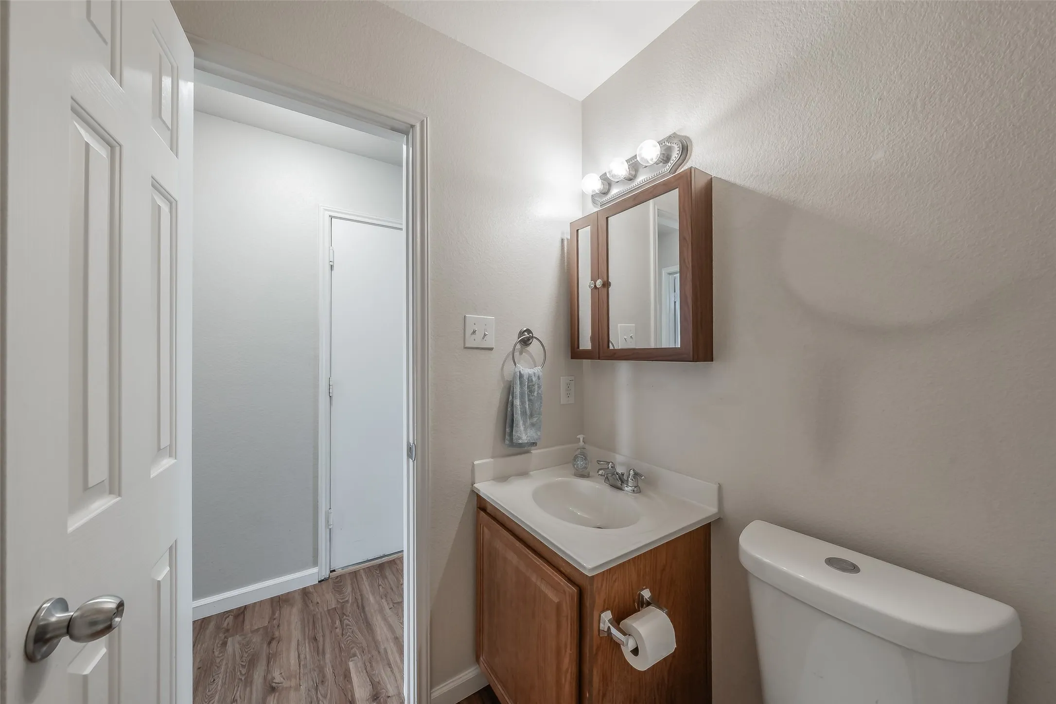 Vanity with wood-finish cabinetry, integrated sink, and medicine cabinet