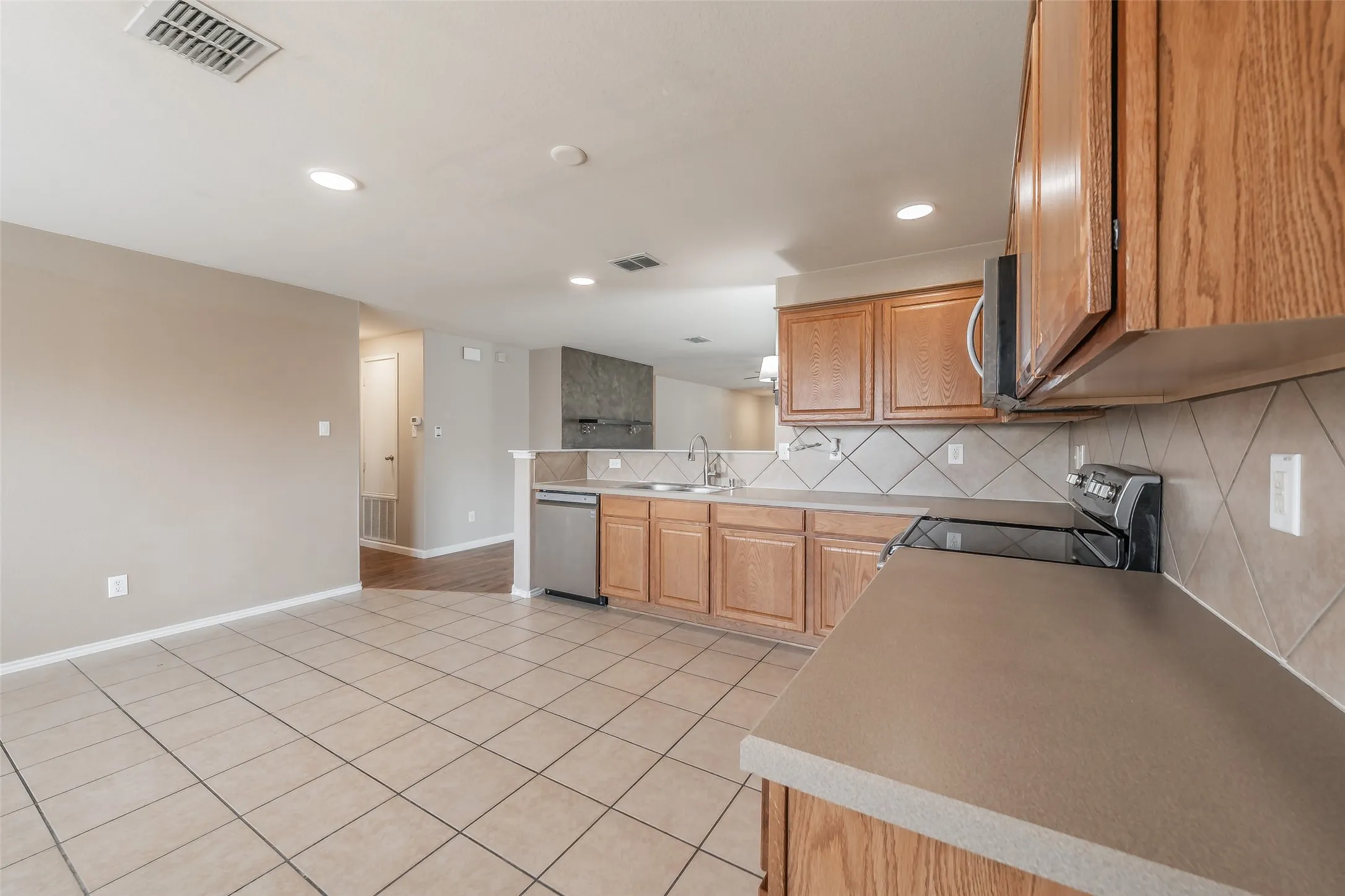 Kitchen featuring wood cabinetry, solid surface countertops, tile backsplash, and stainless steel appliances