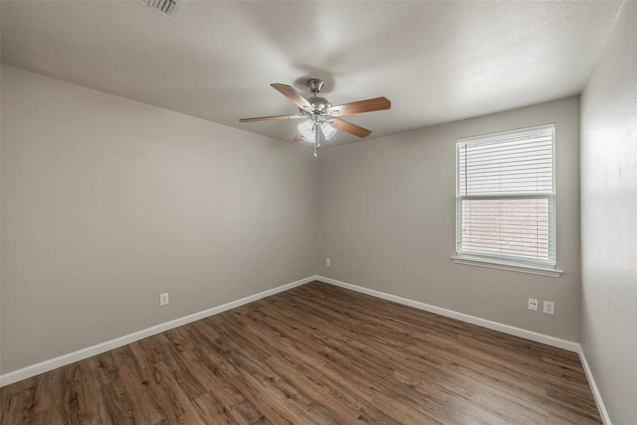 Wood-finish flooring, ceiling fan with light fixture, window with blinds, and neutral wall tones