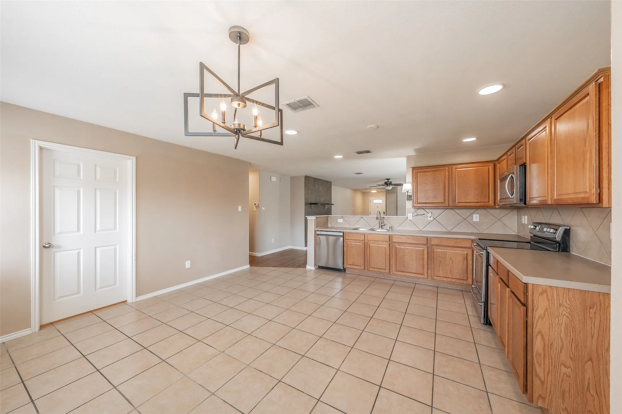 Open-concept kitchen featuring wood cabinetry, stainless steel appliances, and a tiled backsplash