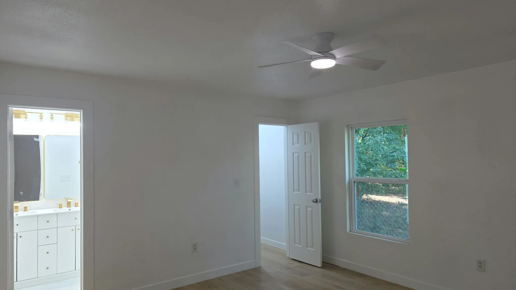 Room featuring a ceiling fan with integrated lighting, wood-finish flooring, and white six-panel interior doors