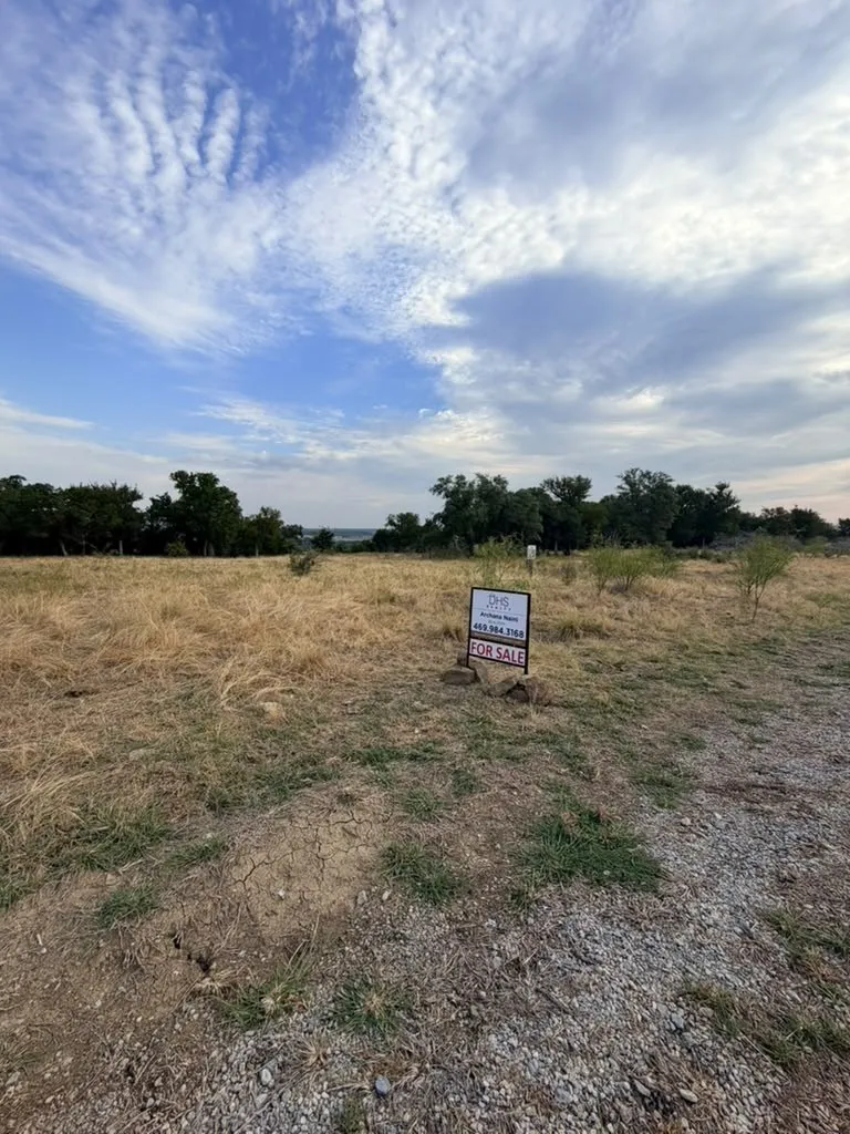 Expansive parcel of land featuring native grasses, mature trees, and natural terrain