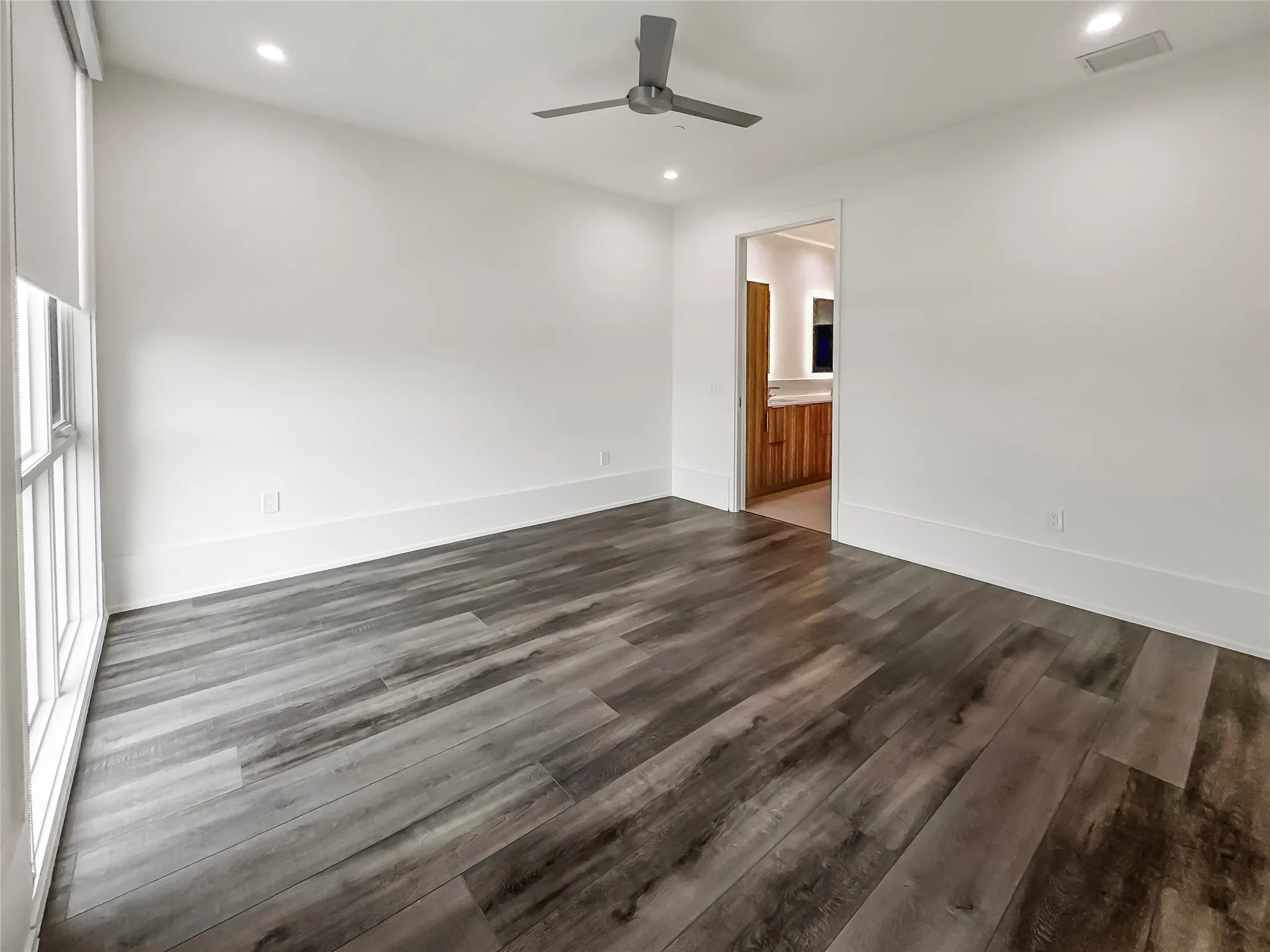 Unfurnished room featuring dark wood-type flooring and ceiling fan