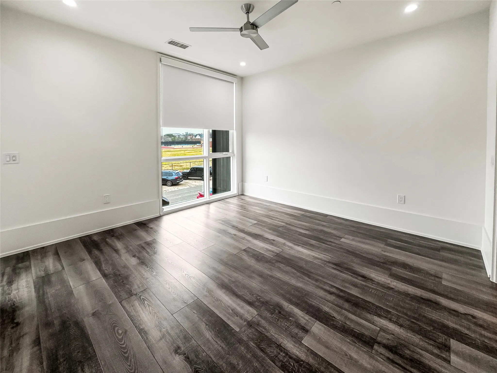 Spare room with dark wood-type flooring, ceiling fan, and a wall of windows