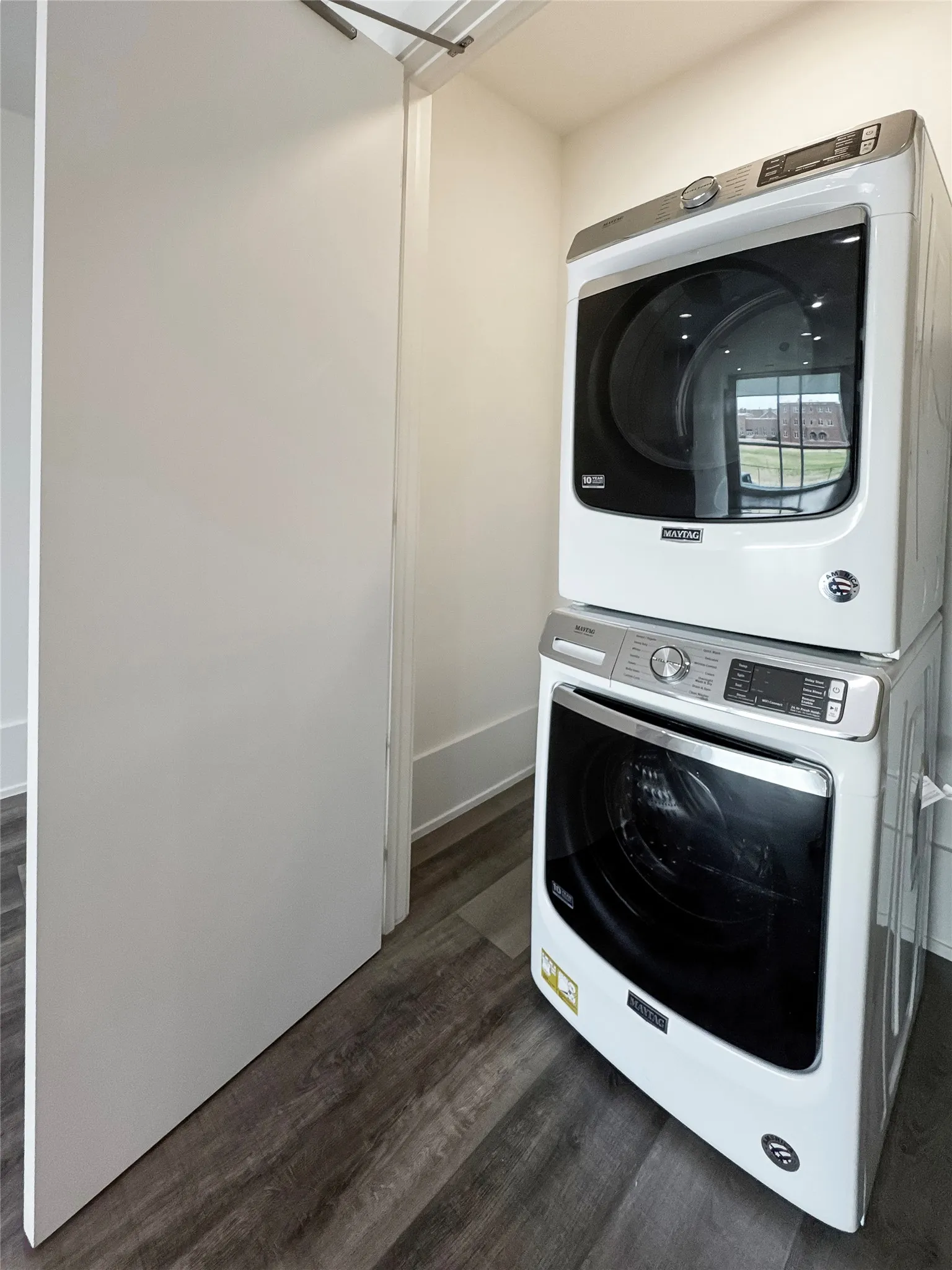 Clothes washing area featuring dark hardwood / wood-style floors and stacked washing maching and dryer
