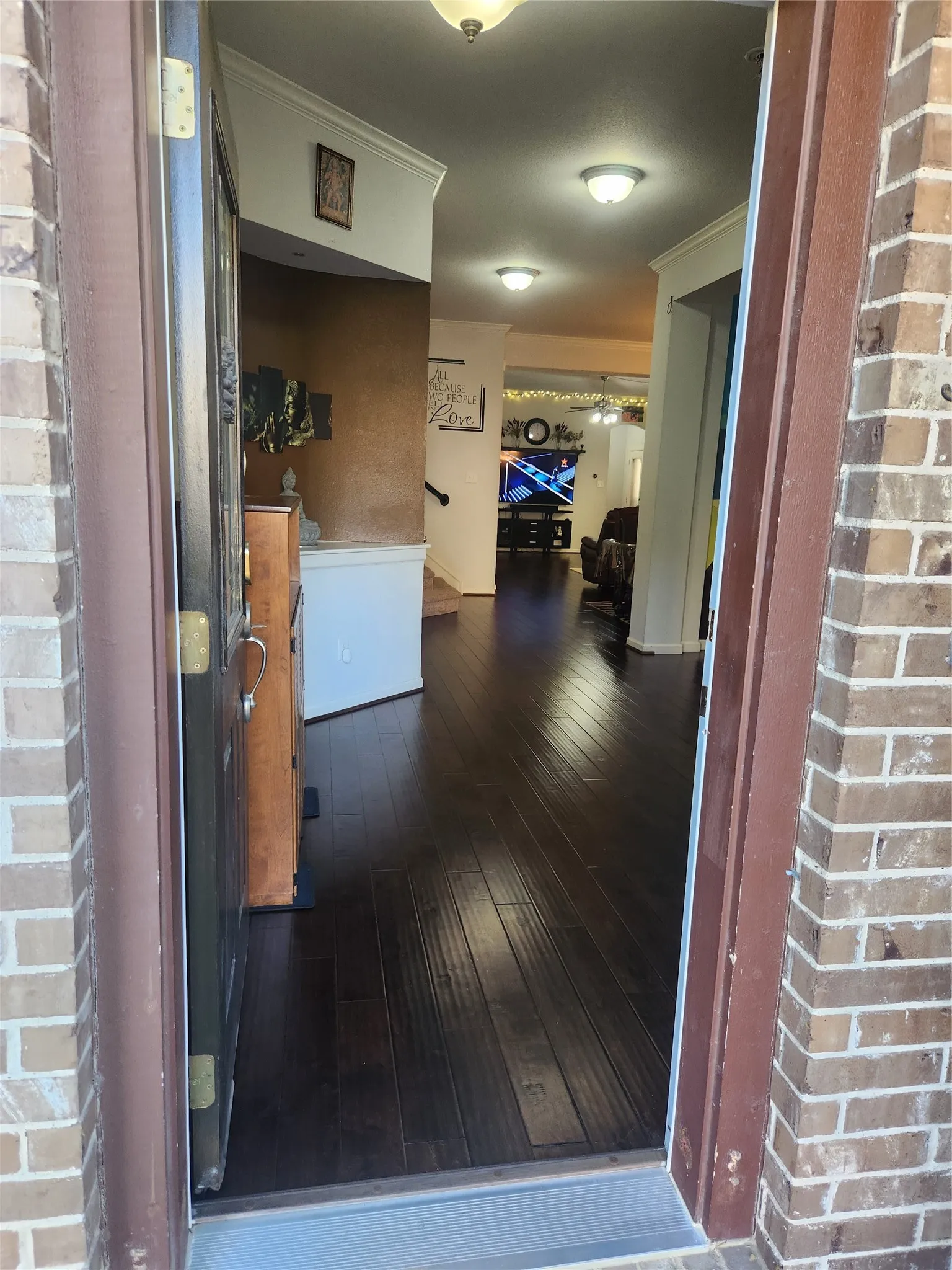 Brick exterior, dark wood-finish flooring, recessed lighting, crown molding, and a built-in staircase