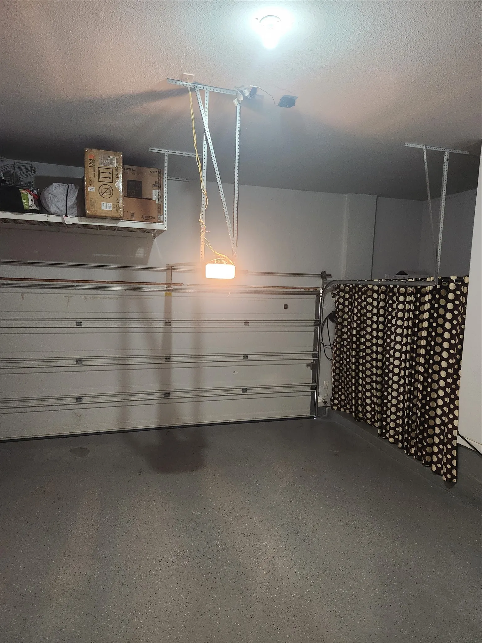 Garage featuring a roll-up door, overhead lighting, an exposed ceiling, and shelving