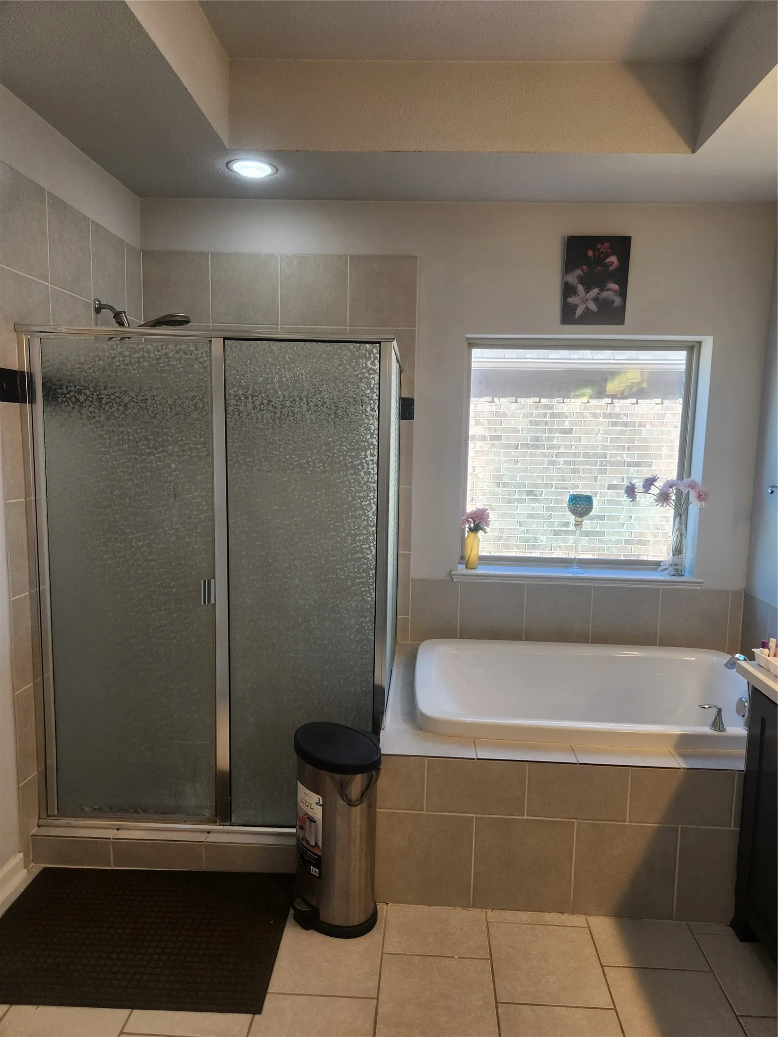 Full bathroom featuring a walk-in shower with sliding frosted glass doors, an inset bathtub, and tiled flooring