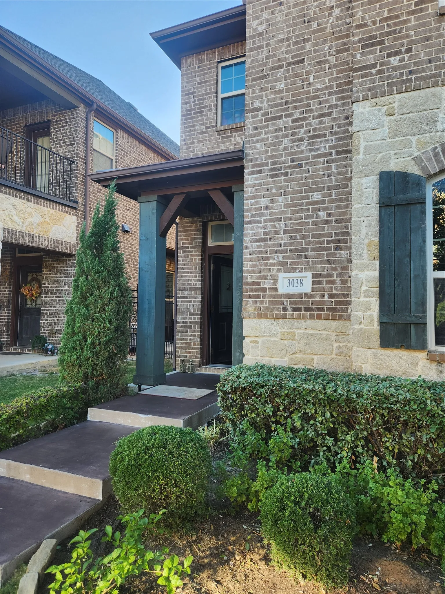 Brick exterior with stone accents, covered entry, and decorative window shutters