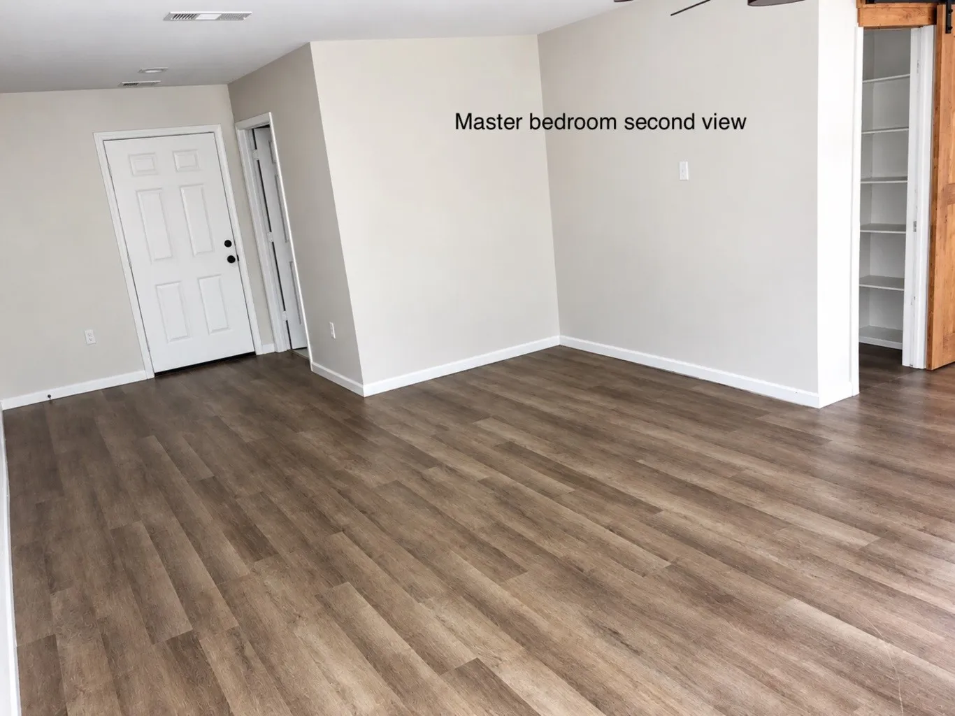 Wood-finish flooring, neutral wall tones, recessed lighting, and built-in shelving unit featuring a sliding wood-finish barn door