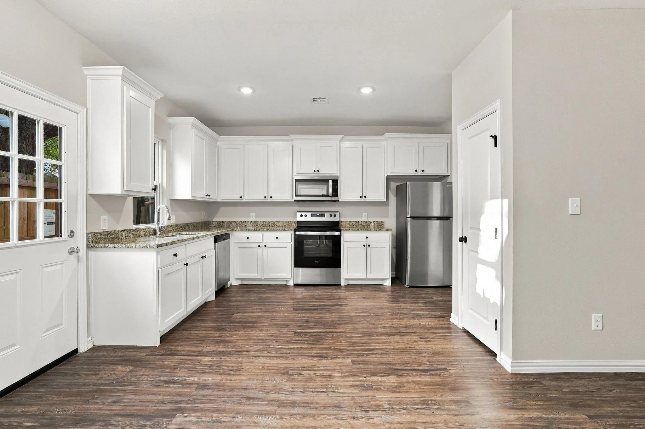 Kitchen featuring white cabinetry, stone-surface countertops, wood-finish flooring, recessed lighting, and stainless steel appliances