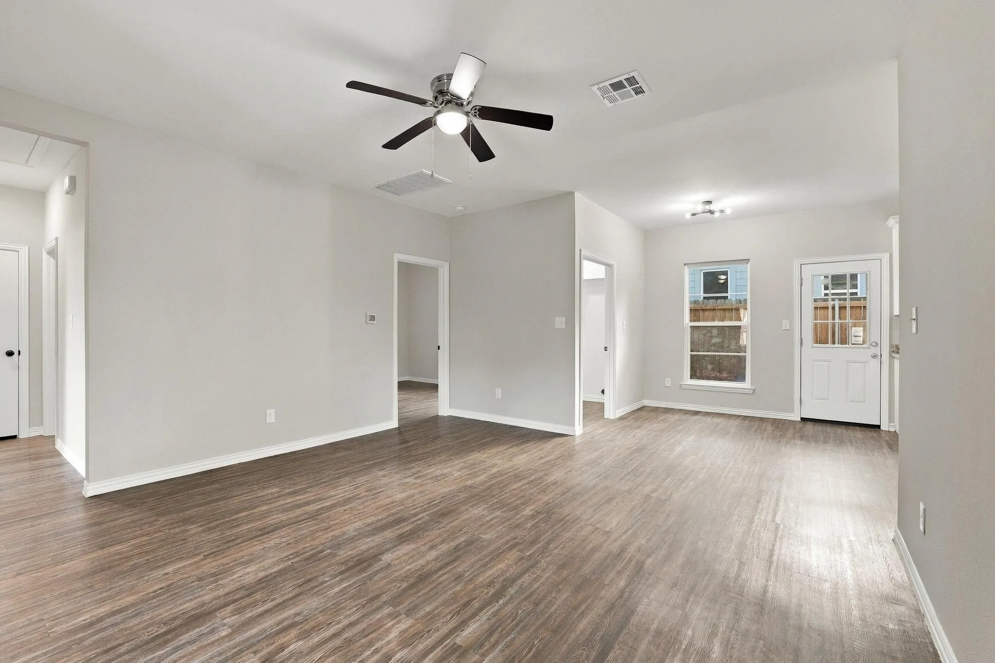 Interior space featuring wood-finish flooring, neutral wall paint, and a ceiling fan with integrated lighting