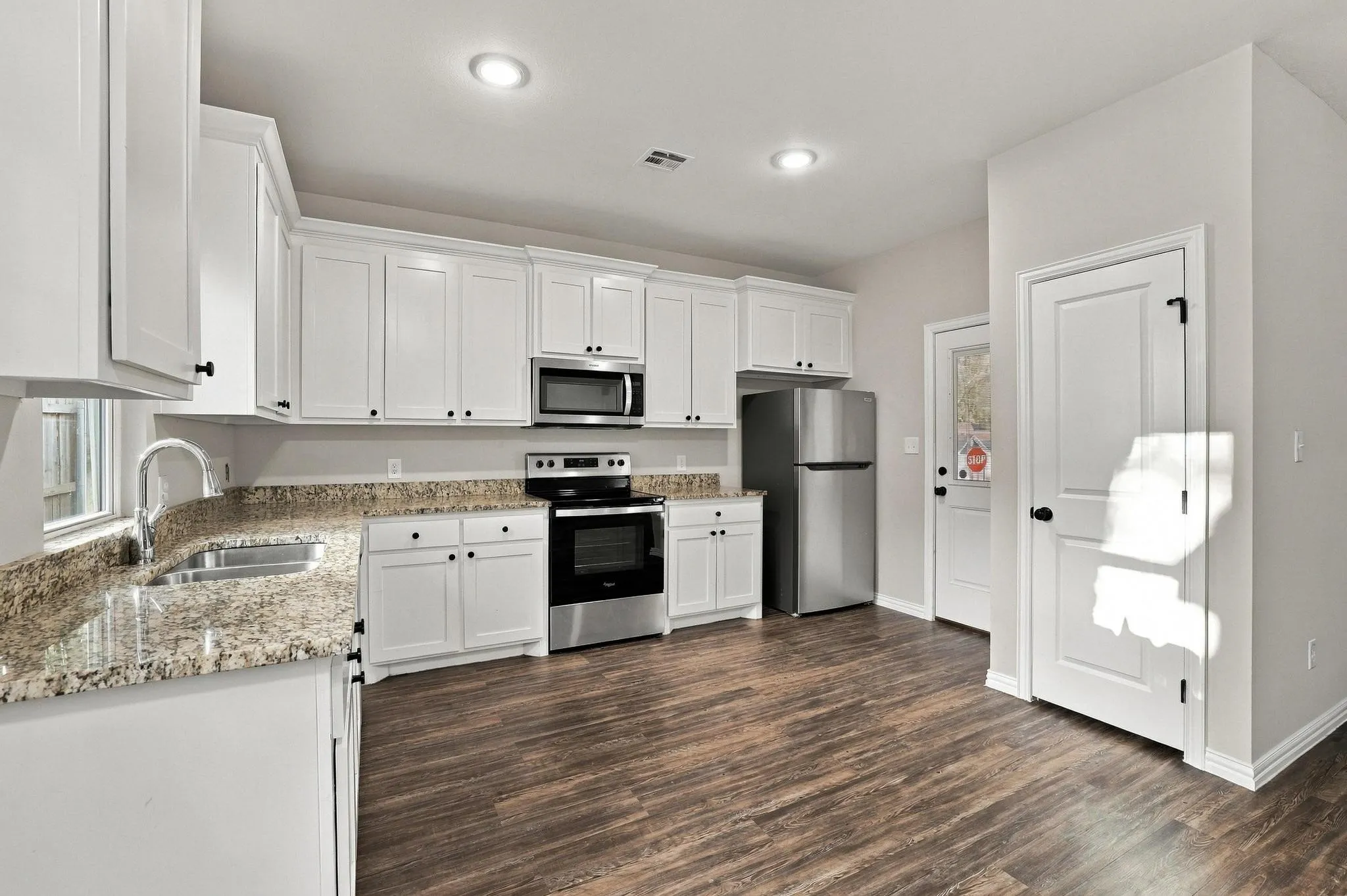 Kitchen featuring white cabinetry, stone-finish countertops, stainless steel appliances, recessed lighting, and wood-finish flooring