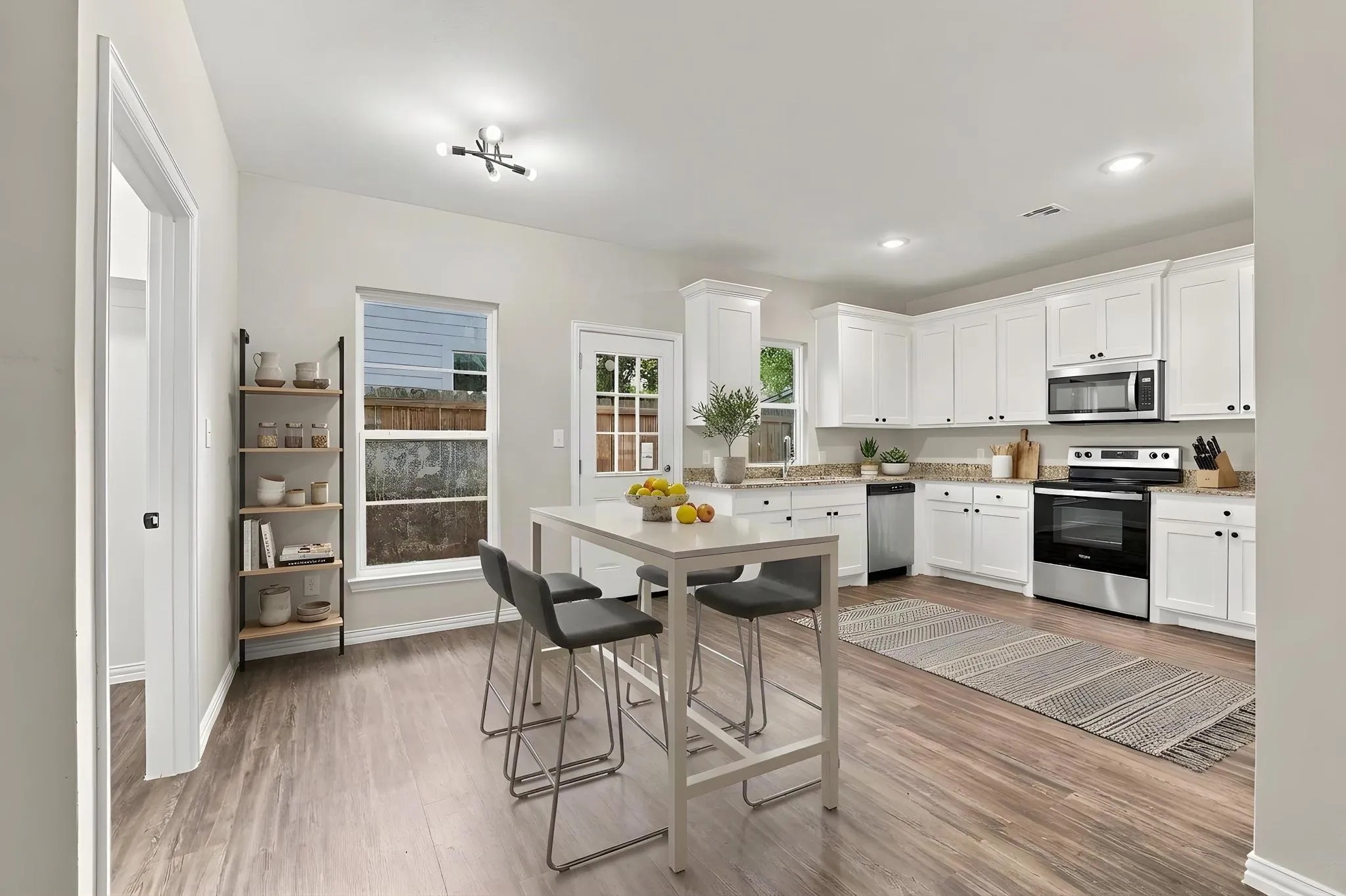 Kitchen featuring white cabinetry, wood-finish flooring, stainless steel appliances, quartz countertops, and recessed lighting