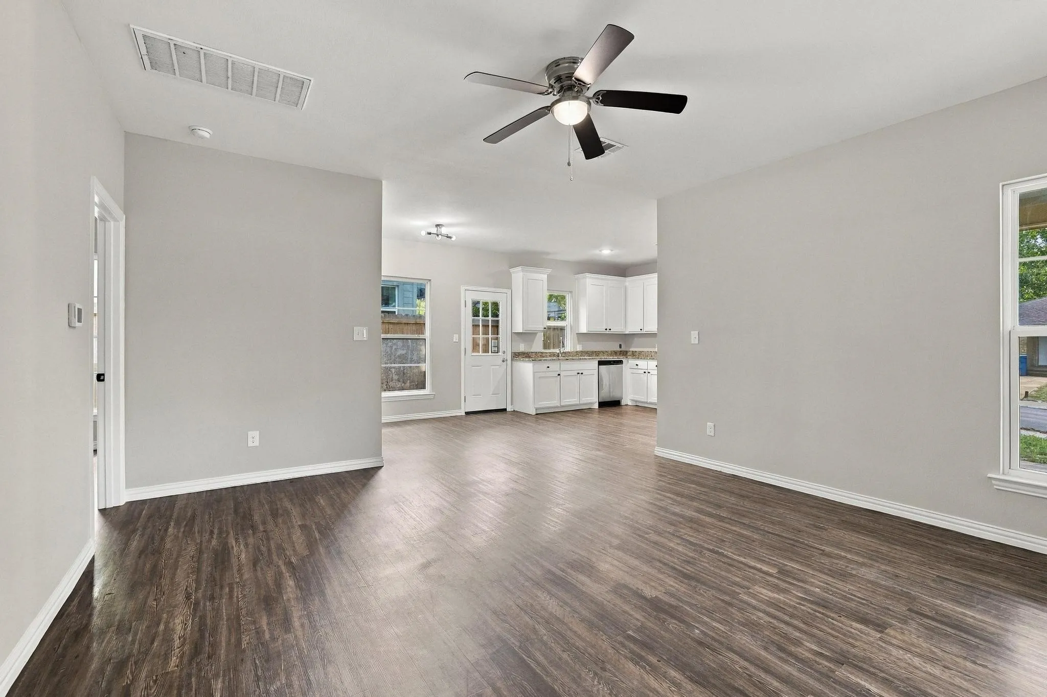 Open-concept interior featuring wood-finish flooring, neutral wall paint, recessed lighting, and a ceiling fan with integrated light fixture
