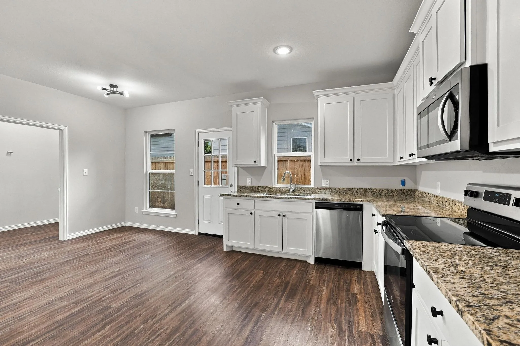Kitchen featuring white cabinetry, stone-finish countertops, stainless steel appliances, and wood-finish flooring