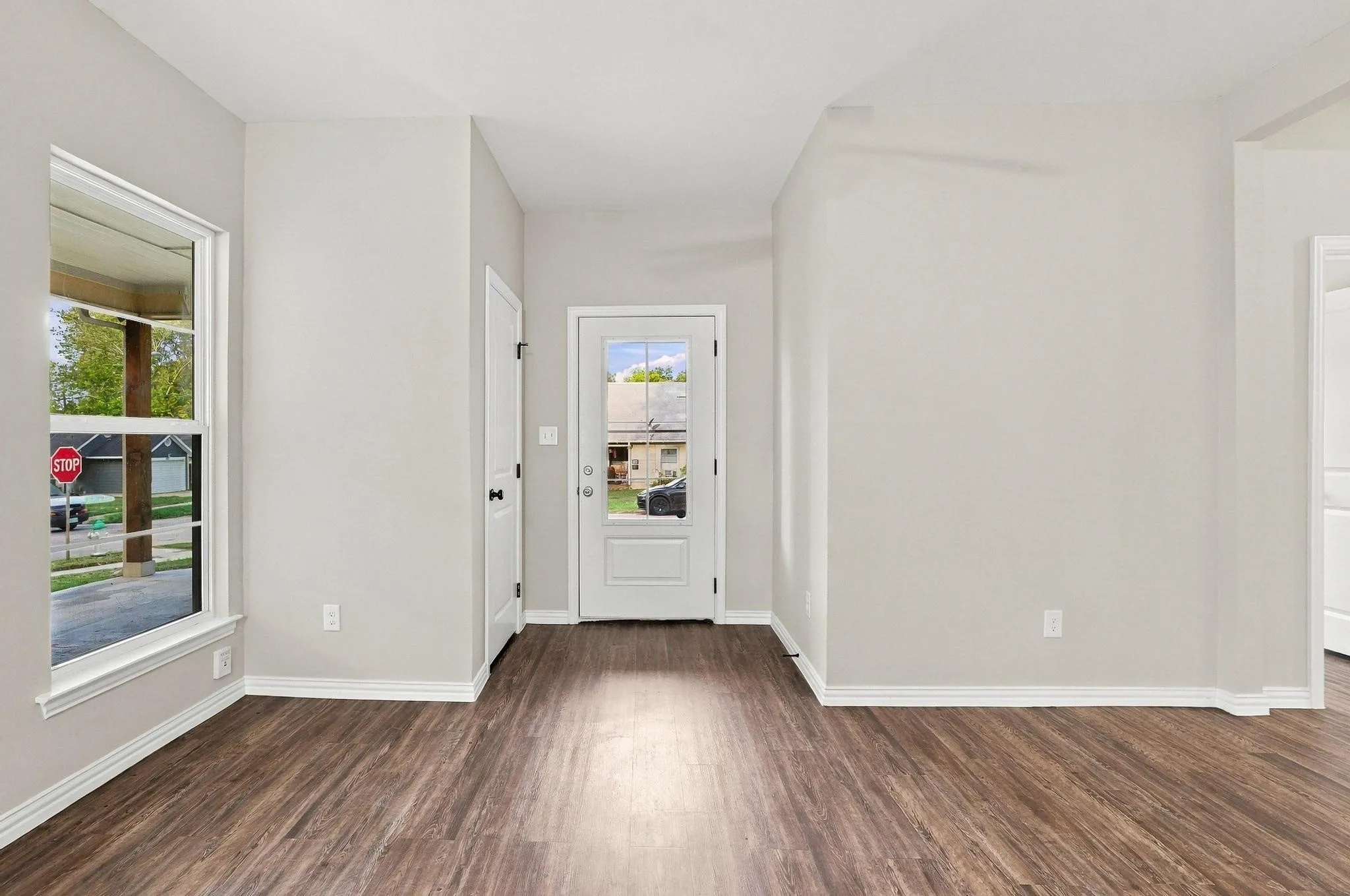 Entryway featuring wood-finish flooring, a neutral color palette, a glass-panel entry door, and a tall window with natural light