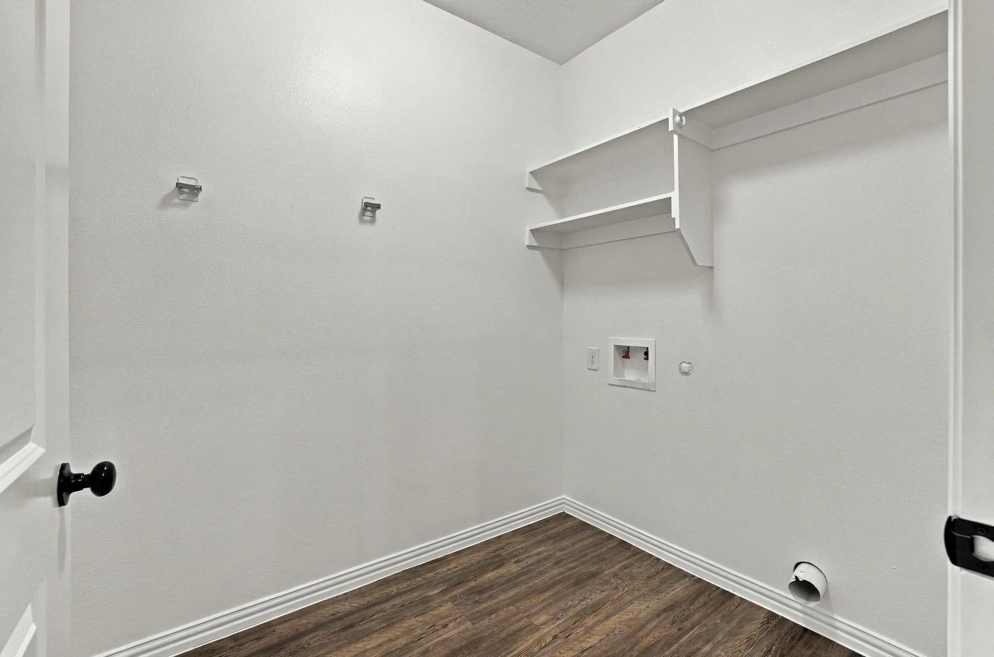 Utility room featuring wood-finish flooring, white walls, and built-in white shelving