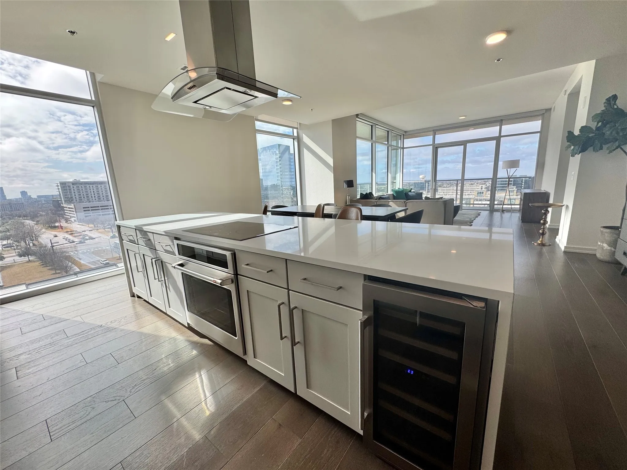Kitchen with a wall of windows, beverage cooler, stainless steel oven, and island exhaust hood