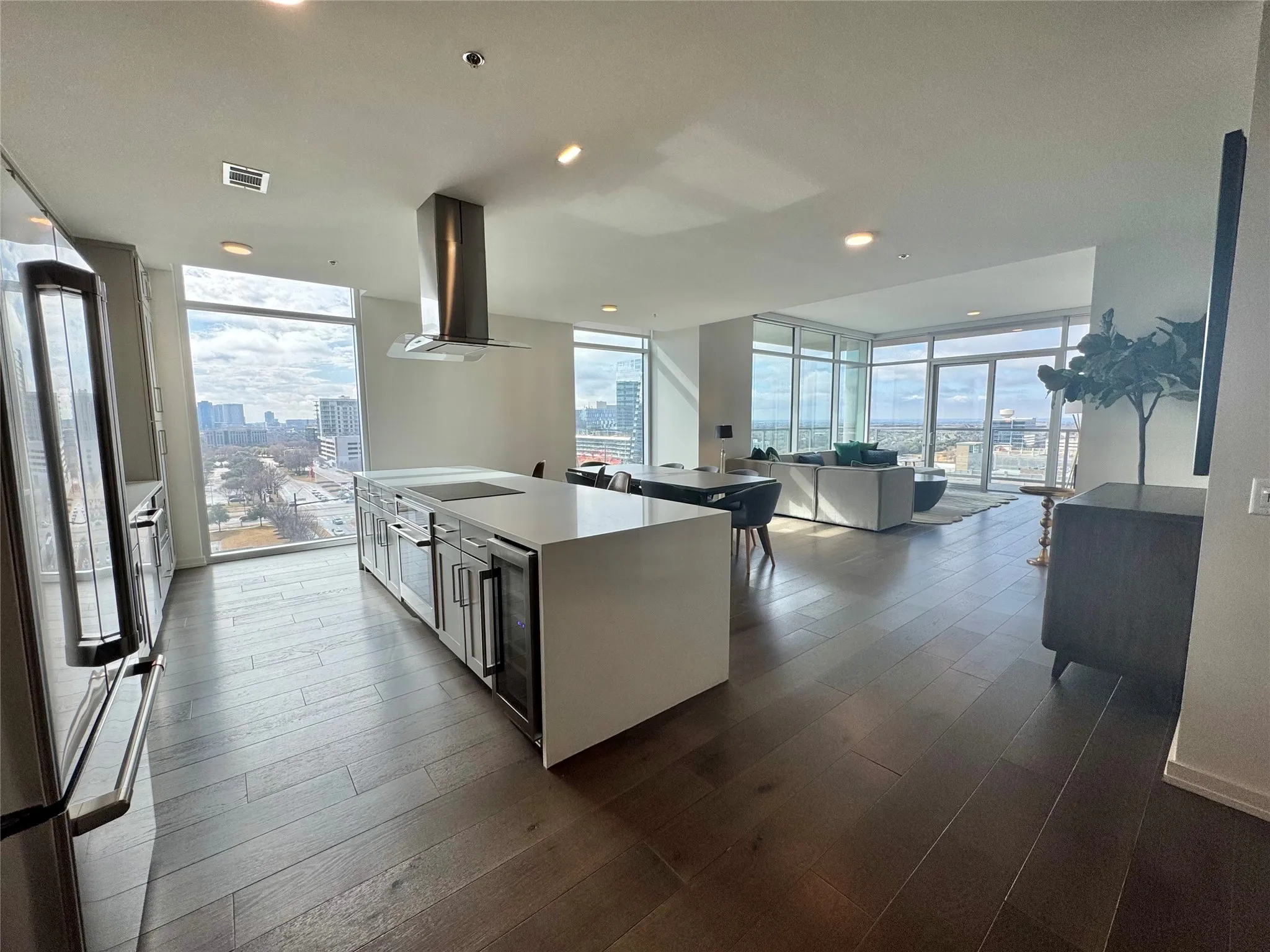 Kitchen featuring expansive windows, island exhaust hood, a kitchen island with sink, and stainless steel appliances