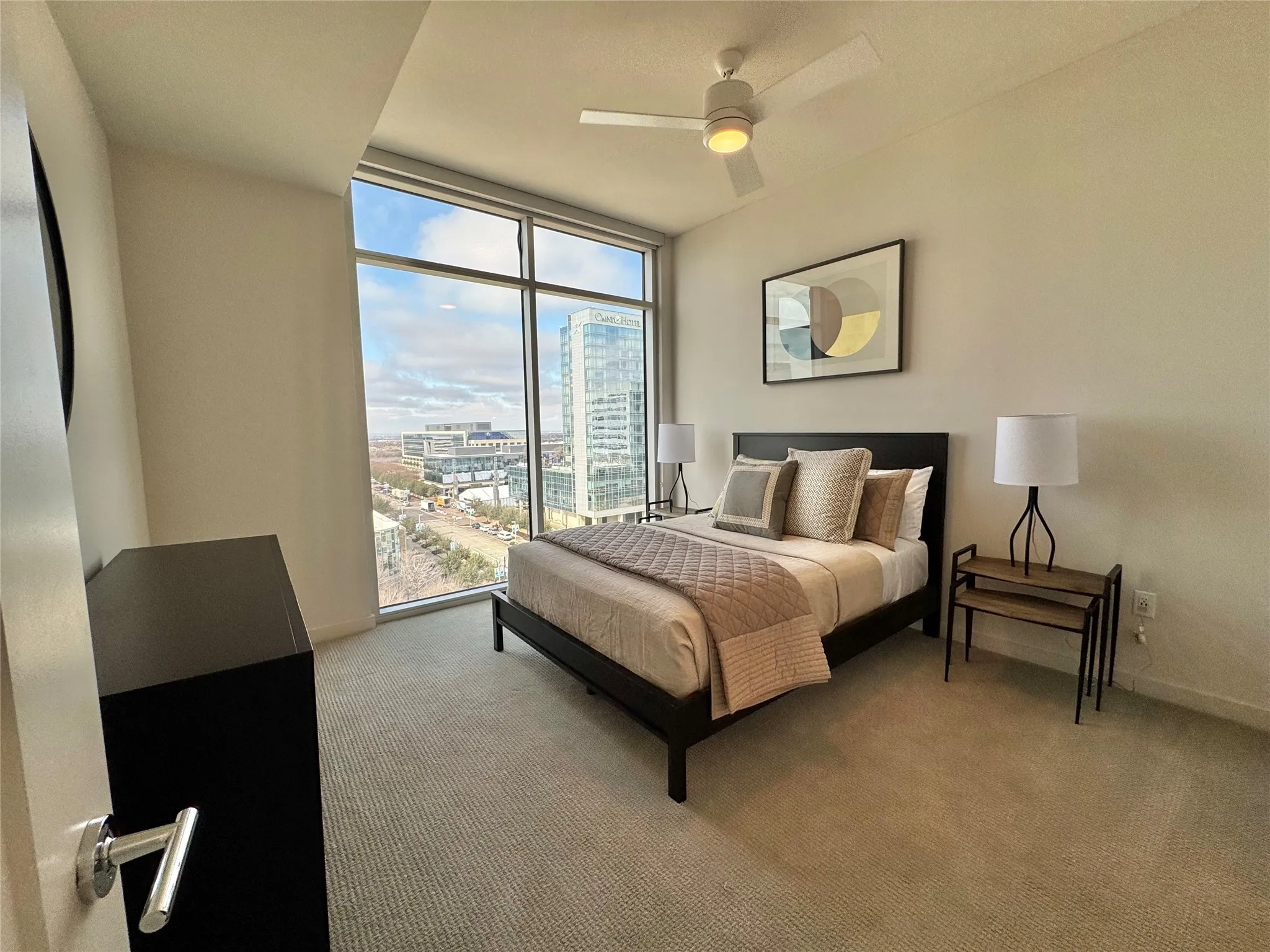Bedroom with expansive windows, light colored carpet, and ceiling fan