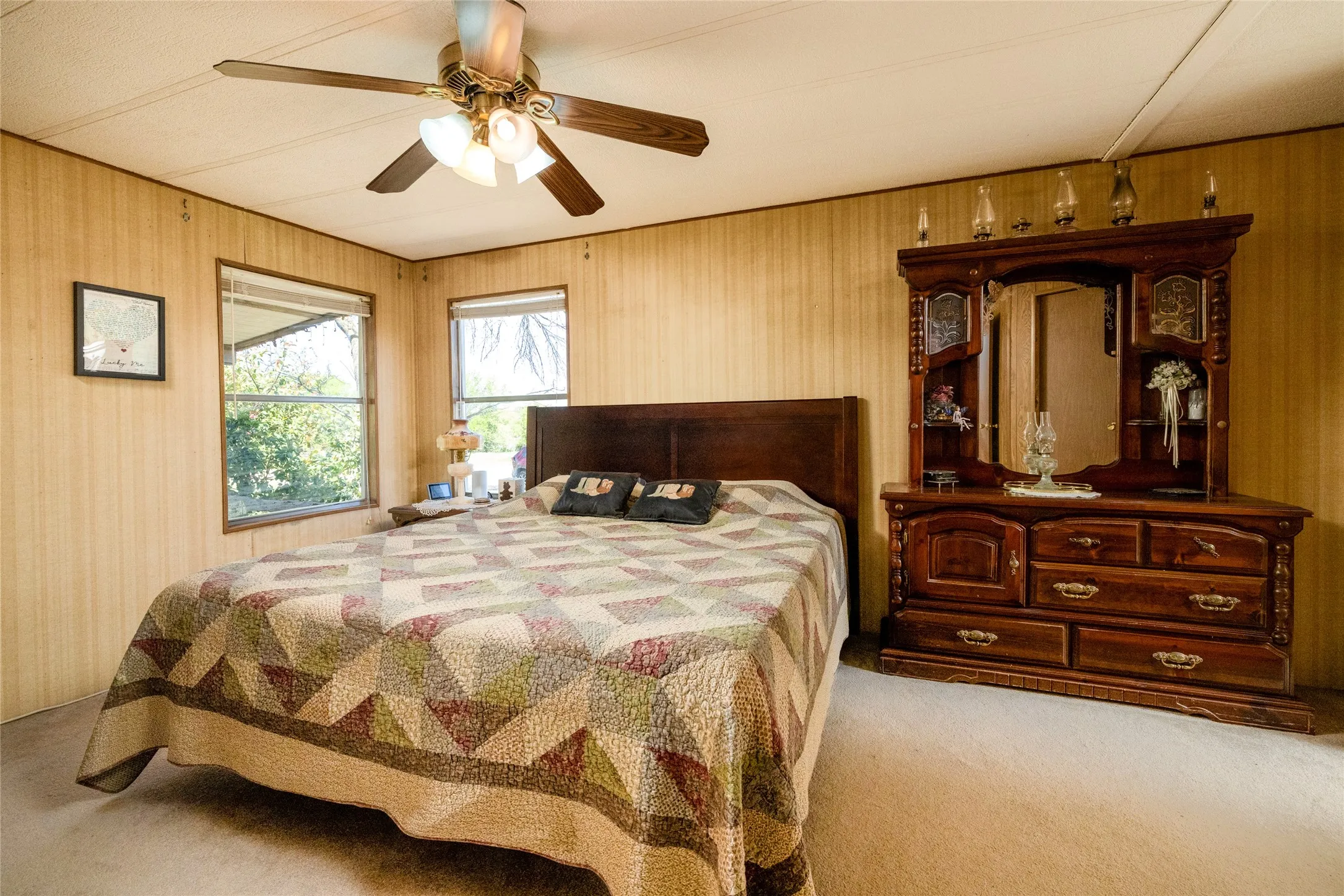 Interior room featuring wood-panel wall finishes, neutral carpeting, and a multi-blade ceiling fan with integrated light fixture