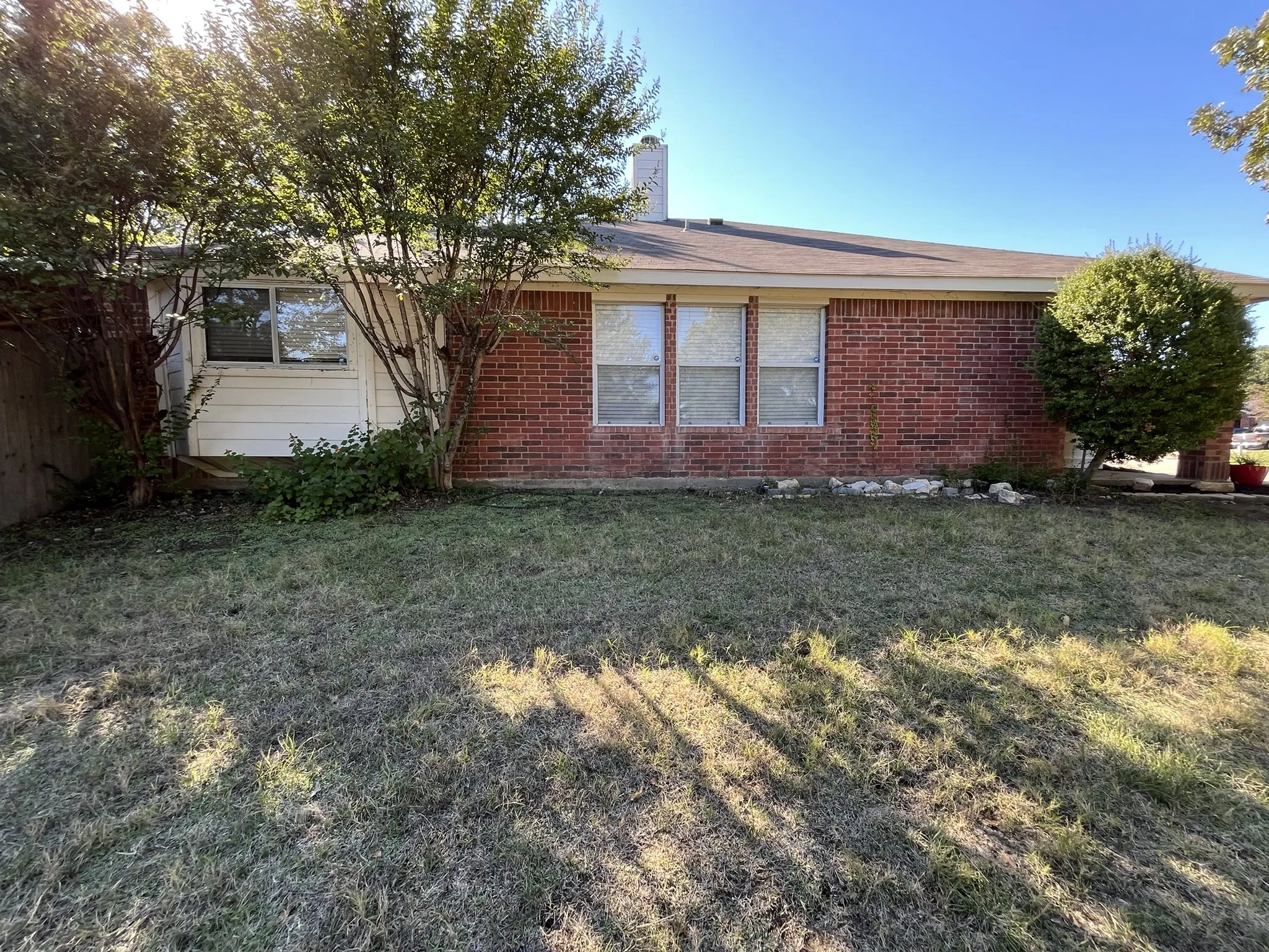 Brick exterior with multiple windows and mature landscaping