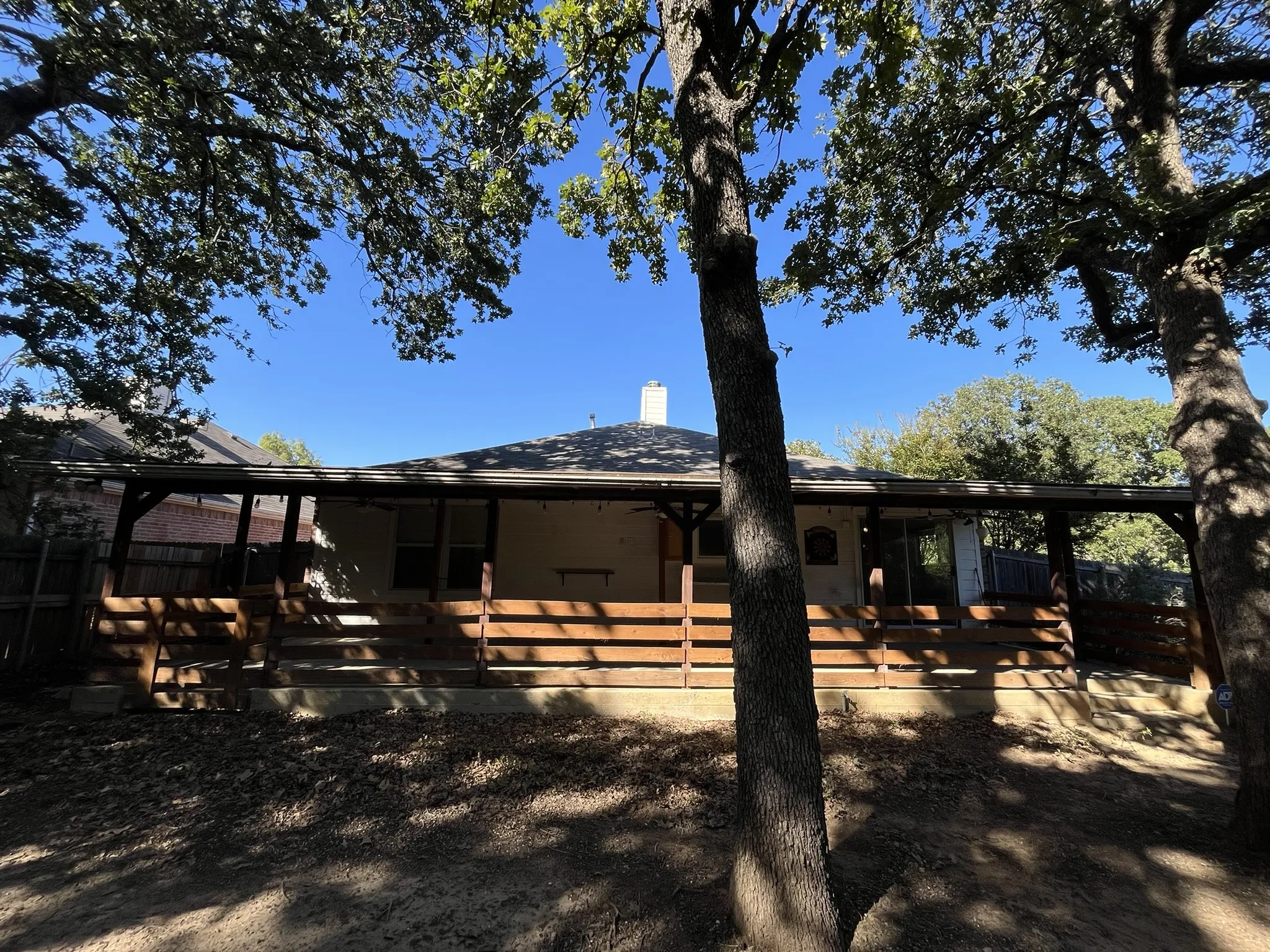 Expansive wood deck with a covered patio area, featuring a pitched roof and exposed wood beams