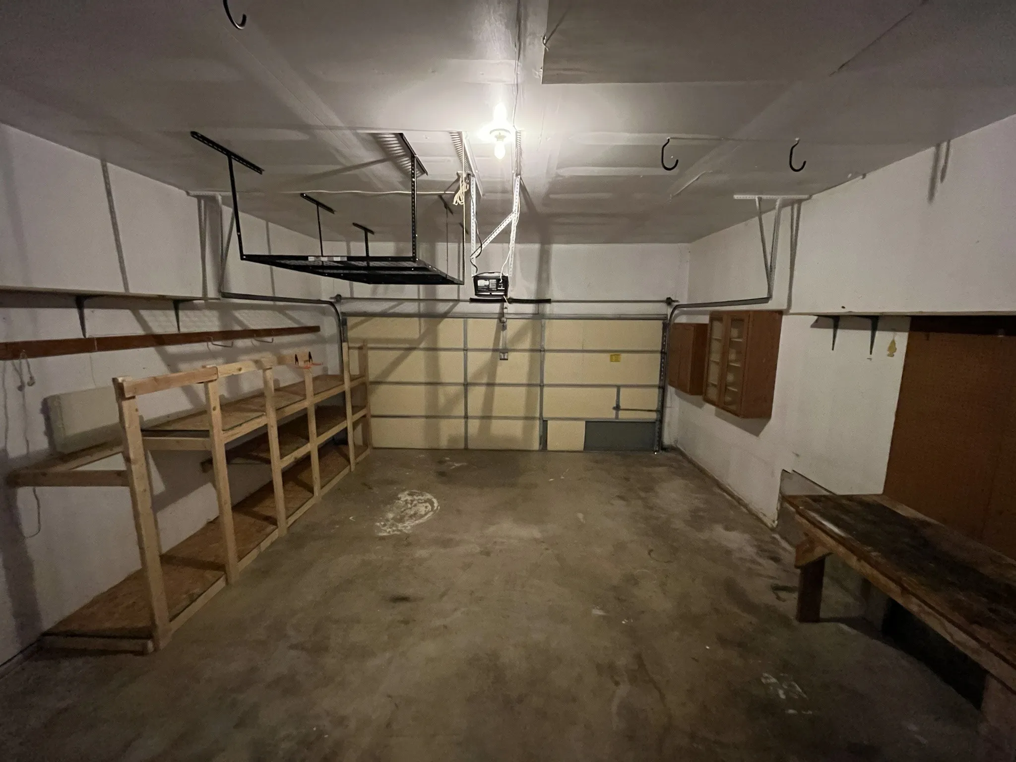 Garage featuring a roll-up door, overhead lighting, and concrete flooring