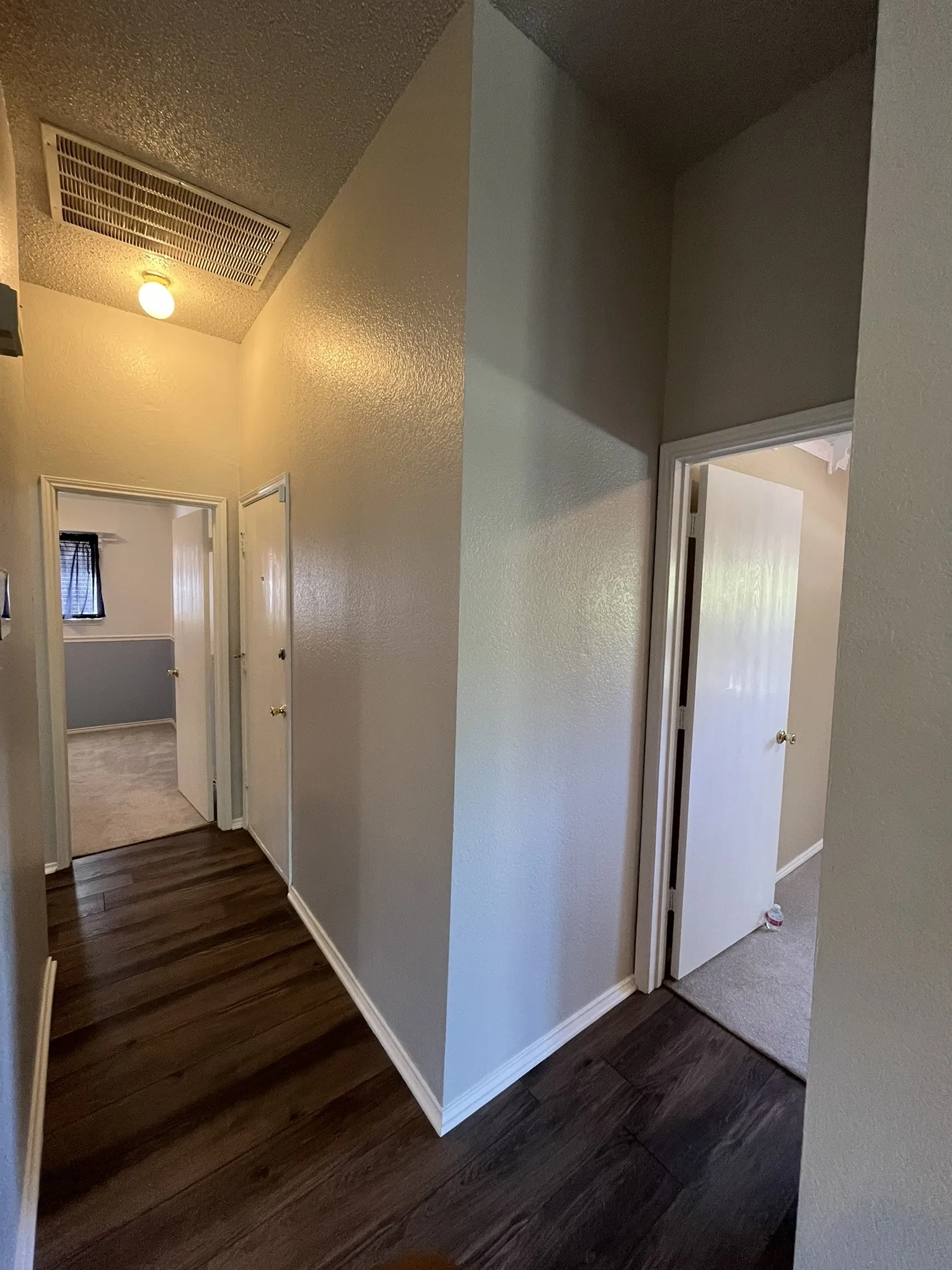 Wood-finish flooring with white trim, neutral-toned walls, and overhead lighting